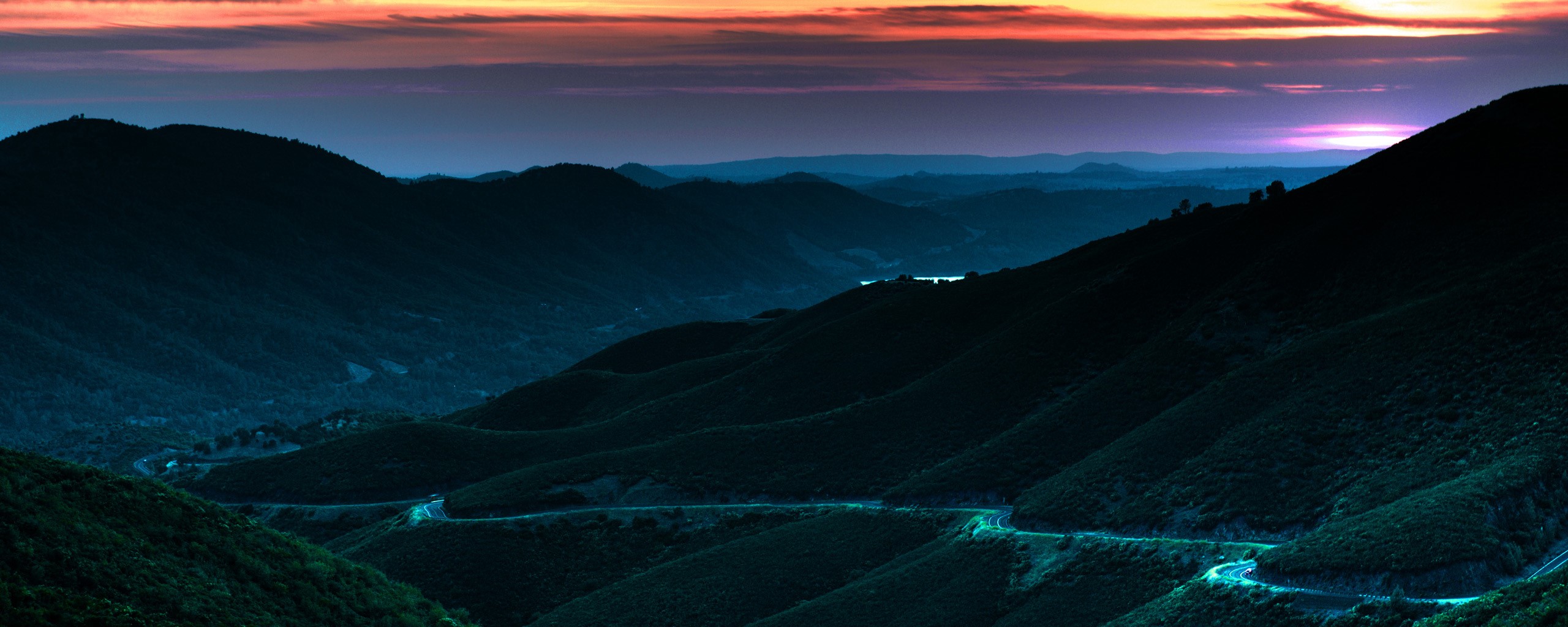 Winding road through mountains at sunset HD Wallpaper