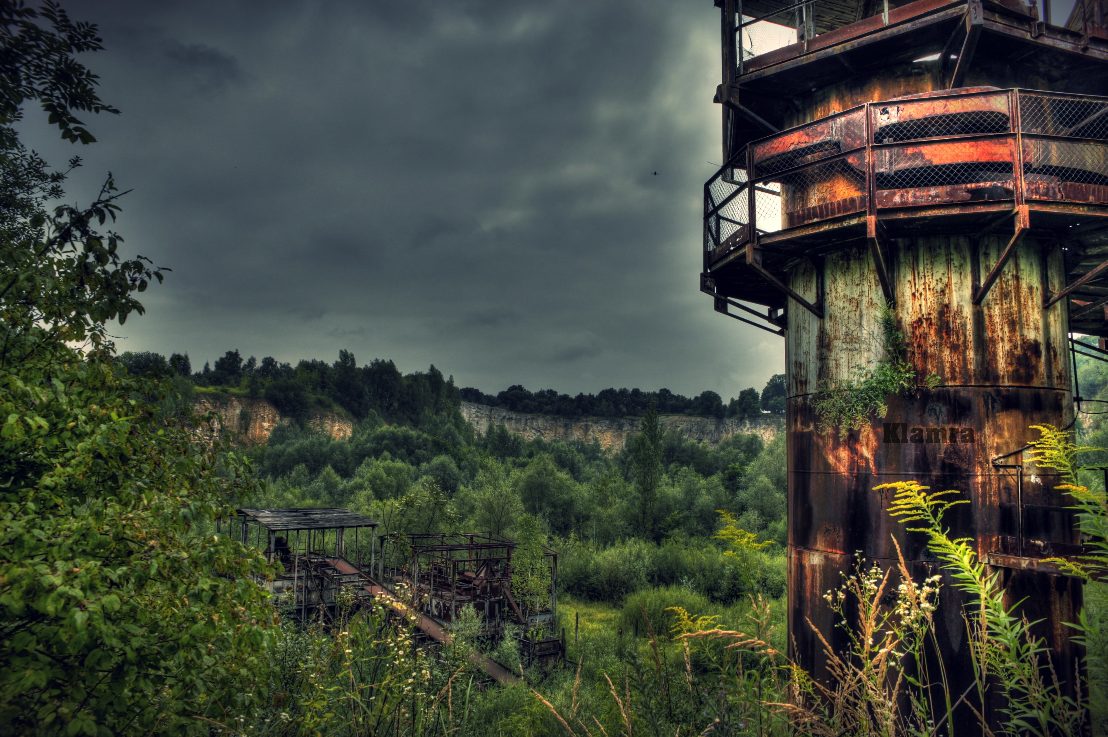 Abandoned industrial tower in overgrown quarry, Poland HD Wallpaper