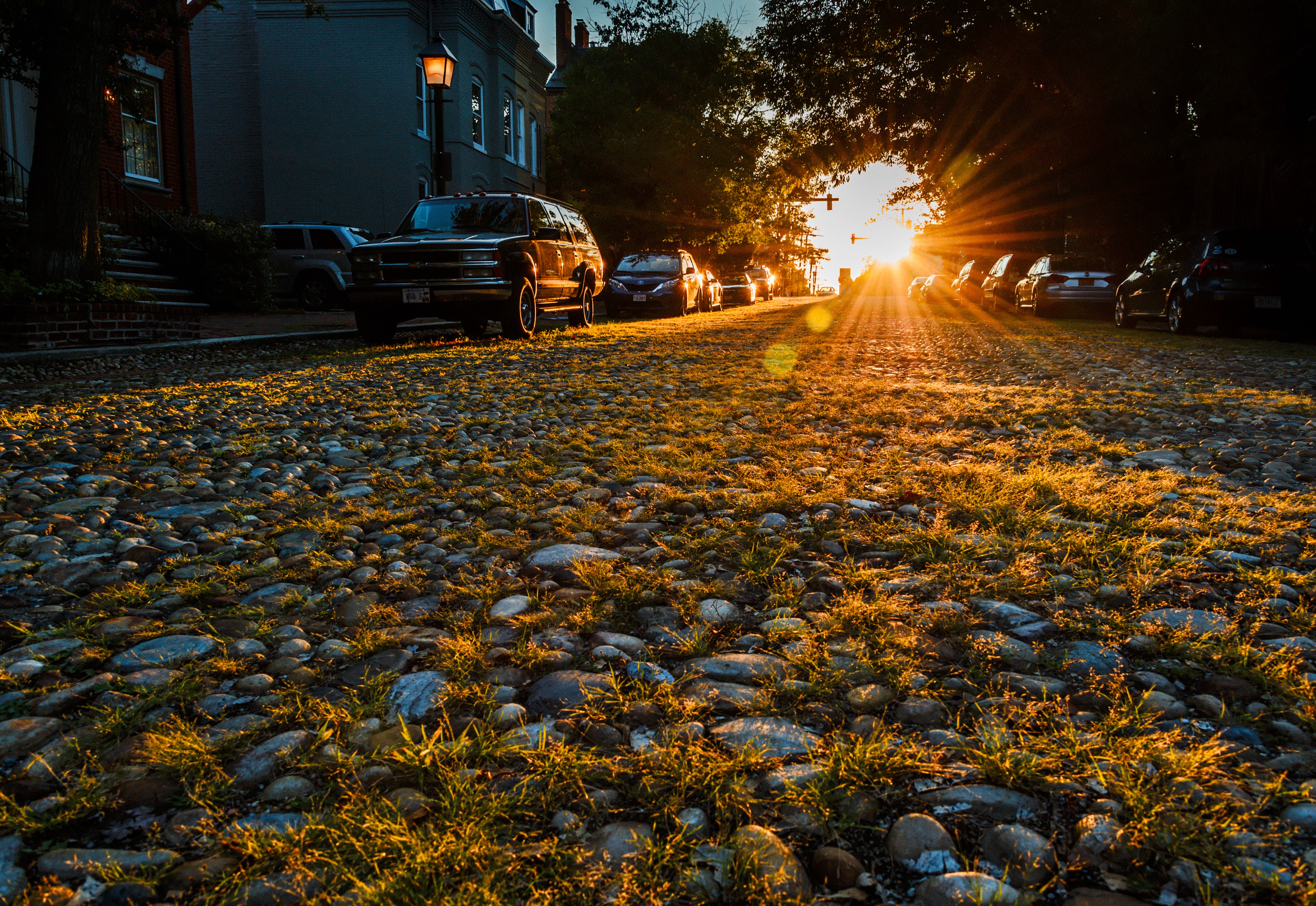 Alexandria street at sunset with cobblestones and cars HD Wallpaper