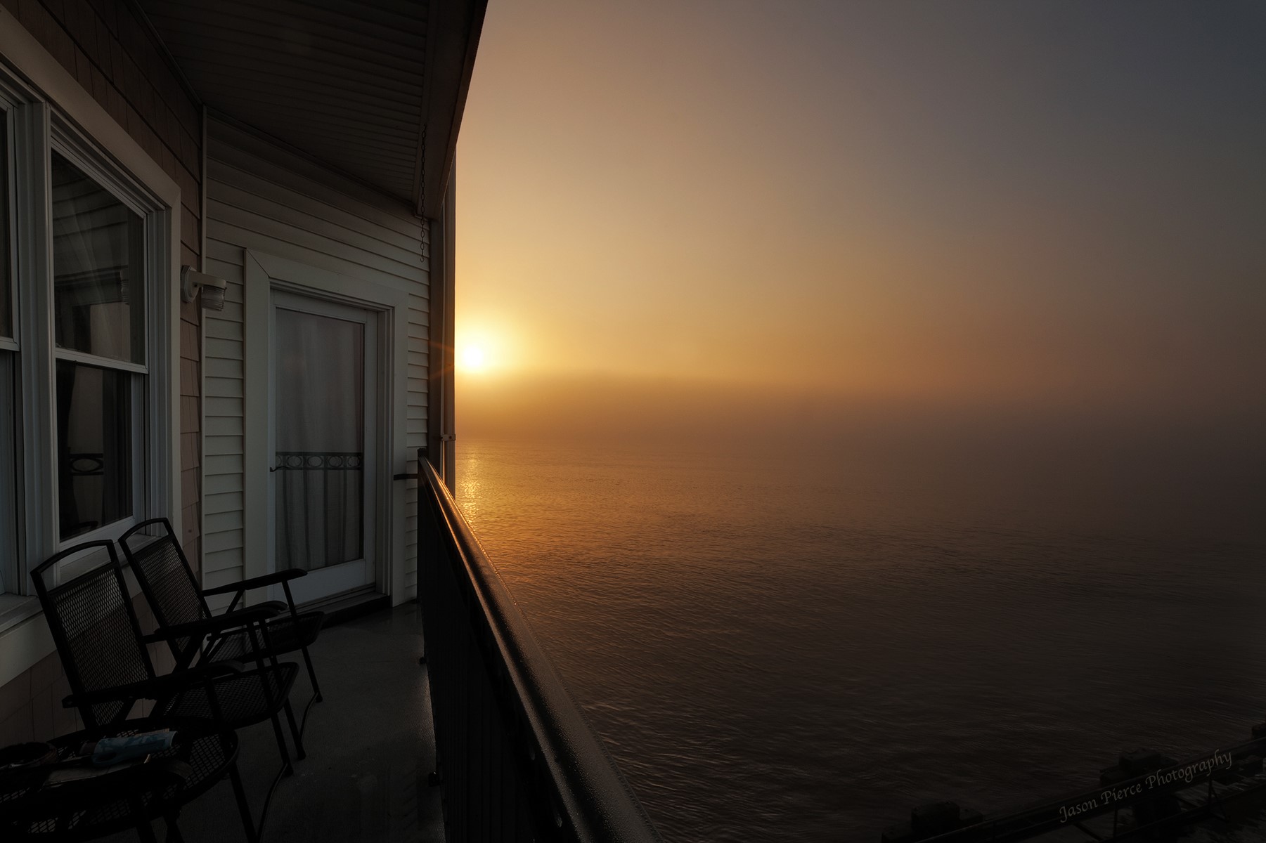 Sunrise over the ocean from a balcony with chairs HD Wallpaper