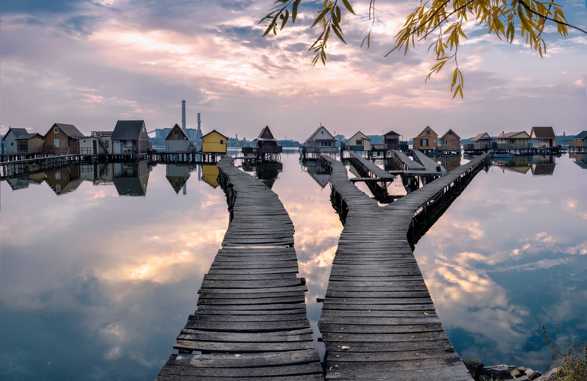 Wooden walkways leading to stilt houses on a lake HD Wallpaper