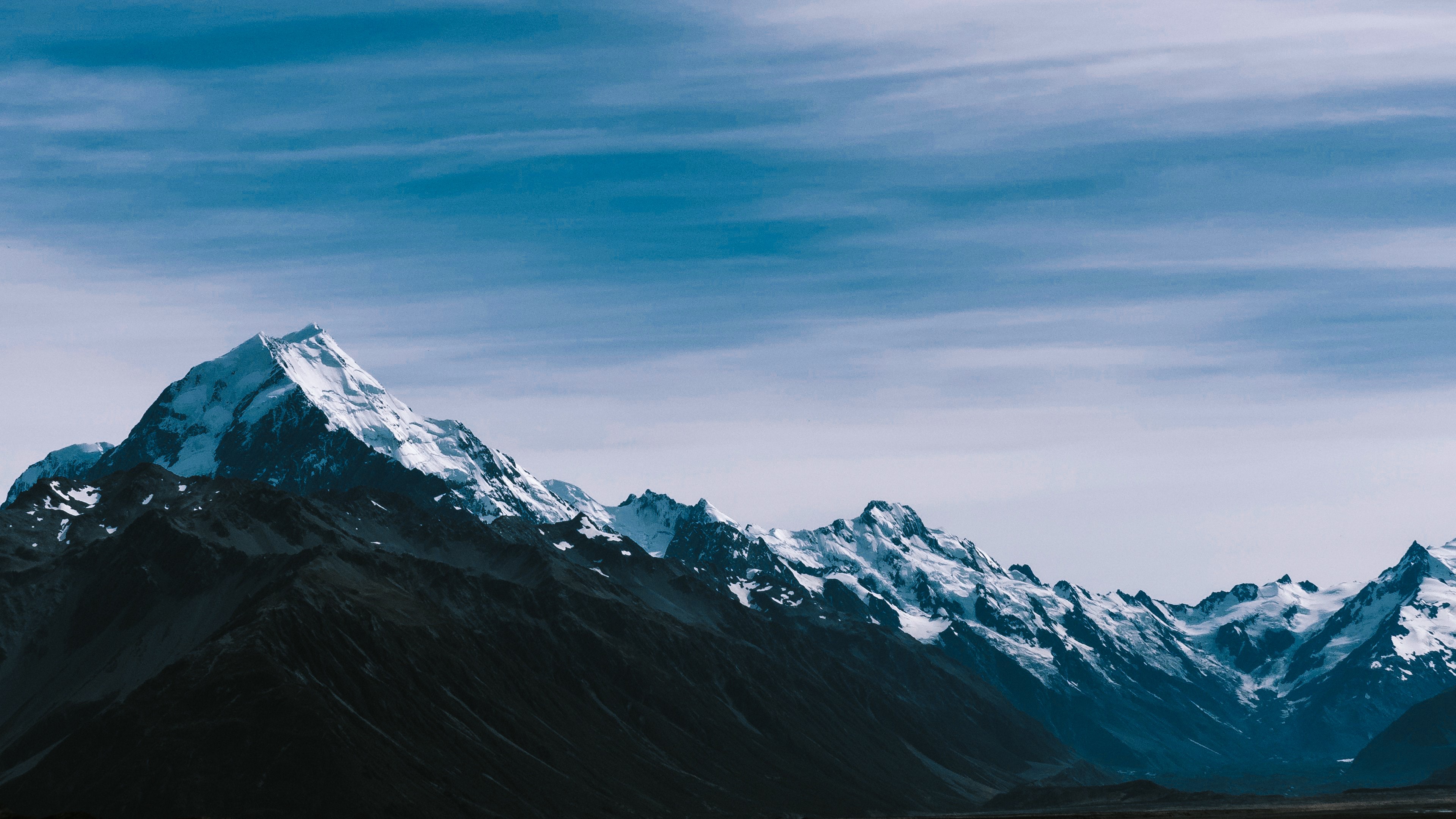 Snow-capped mountains under a cloudy sky HD Wallpaper