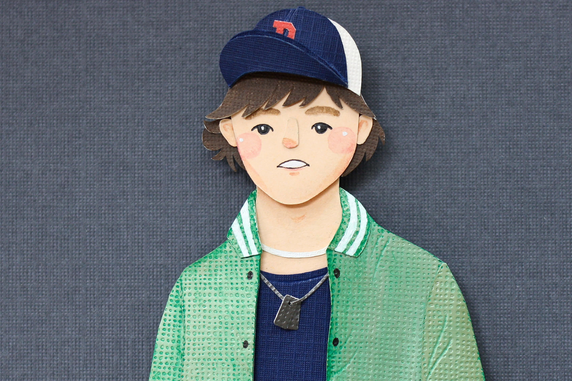 Paper cutout of a young person wearing a baseball cap and jacket HD Wallpaper