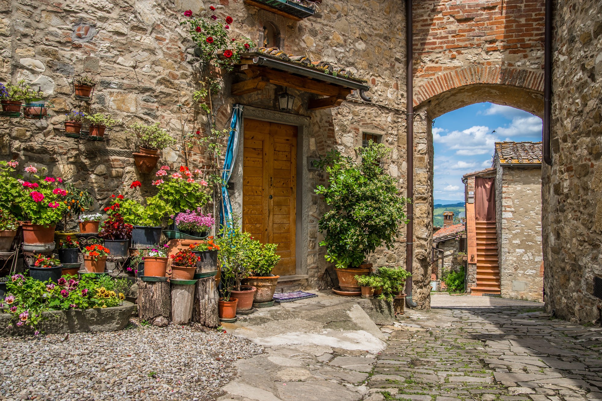 Stone house entrance with potted flowers in Tuscany, Italy HD Wallpaper