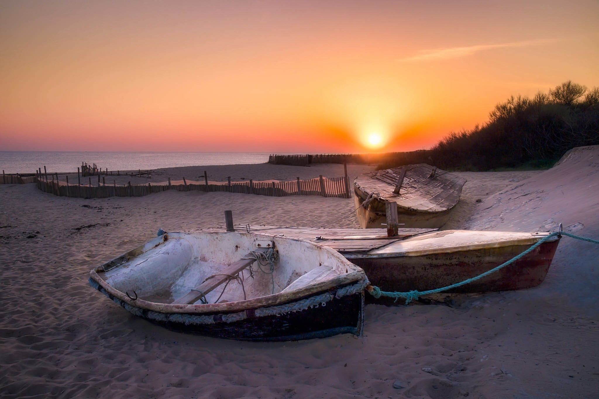 Boats on a sandy beach at sunset HD Wallpaper
