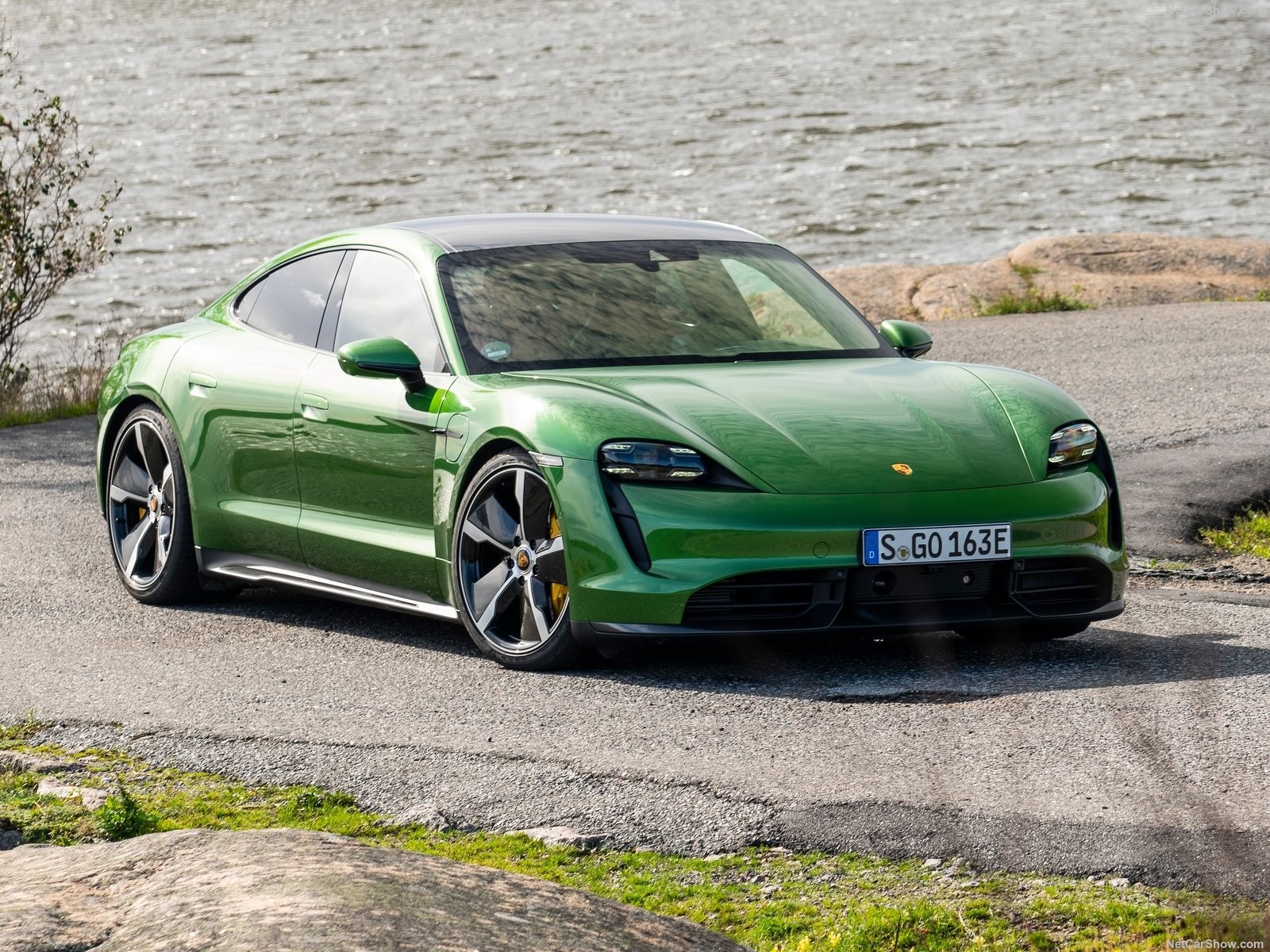 Green Porsche Taycan parked by a body of water HD Wallpaper