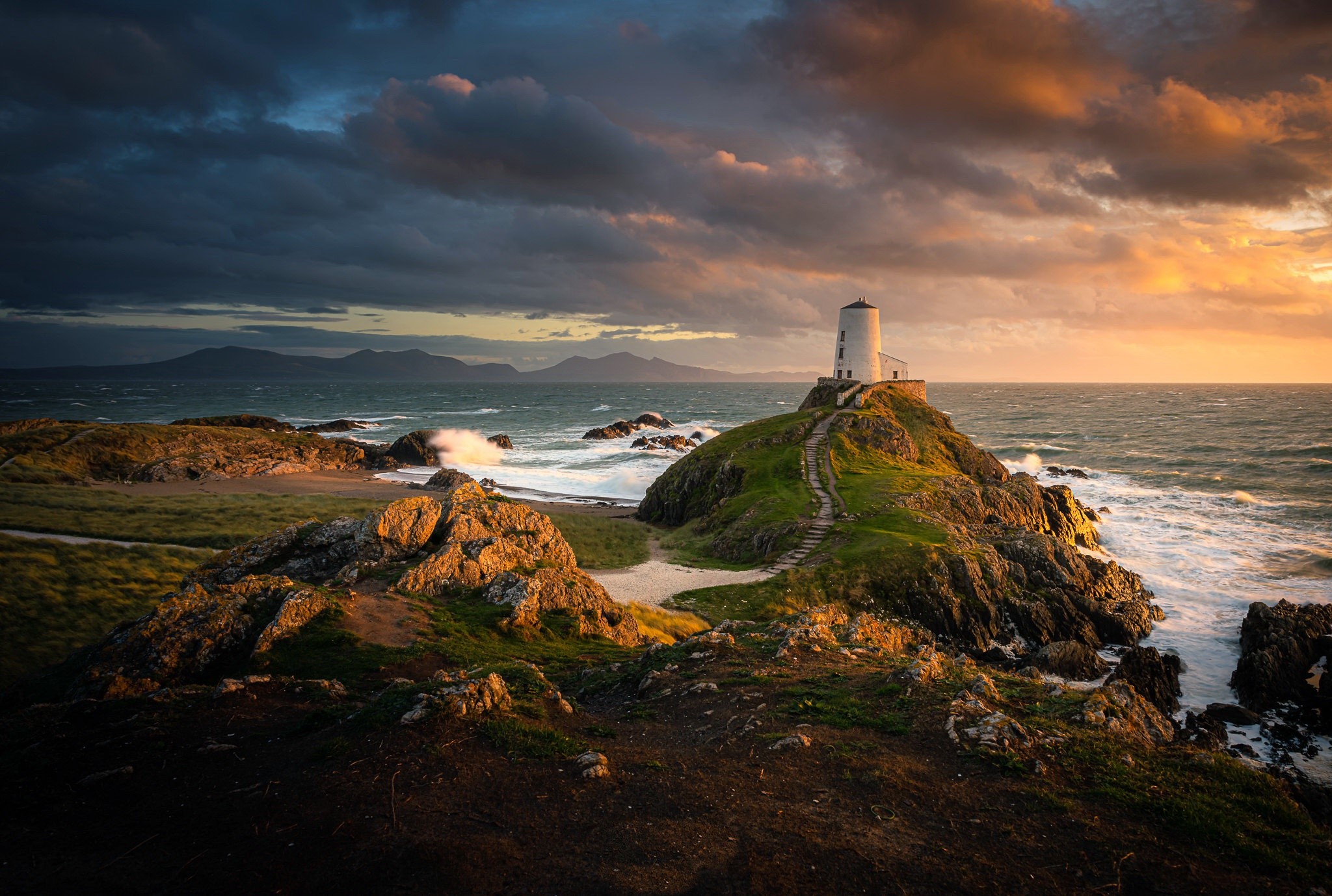 Lighthouse on a rocky coast in Wales at sunset HD Wallpaper