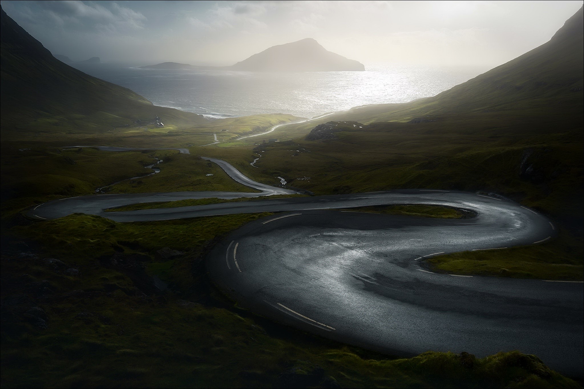 Winding wet road through a green valley to the sea HD Wallpaper