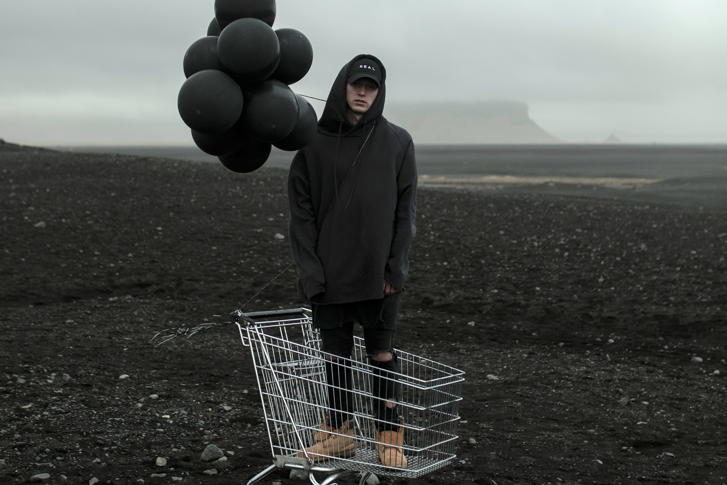 Man with black balloons in a shopping cart HD Wallpaper