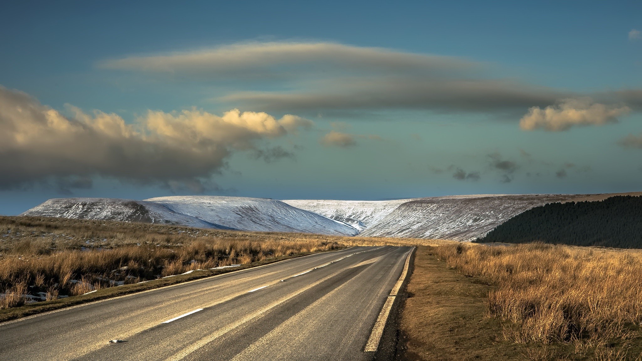 Road through snowy hills under cloudy sky HD Wallpaper