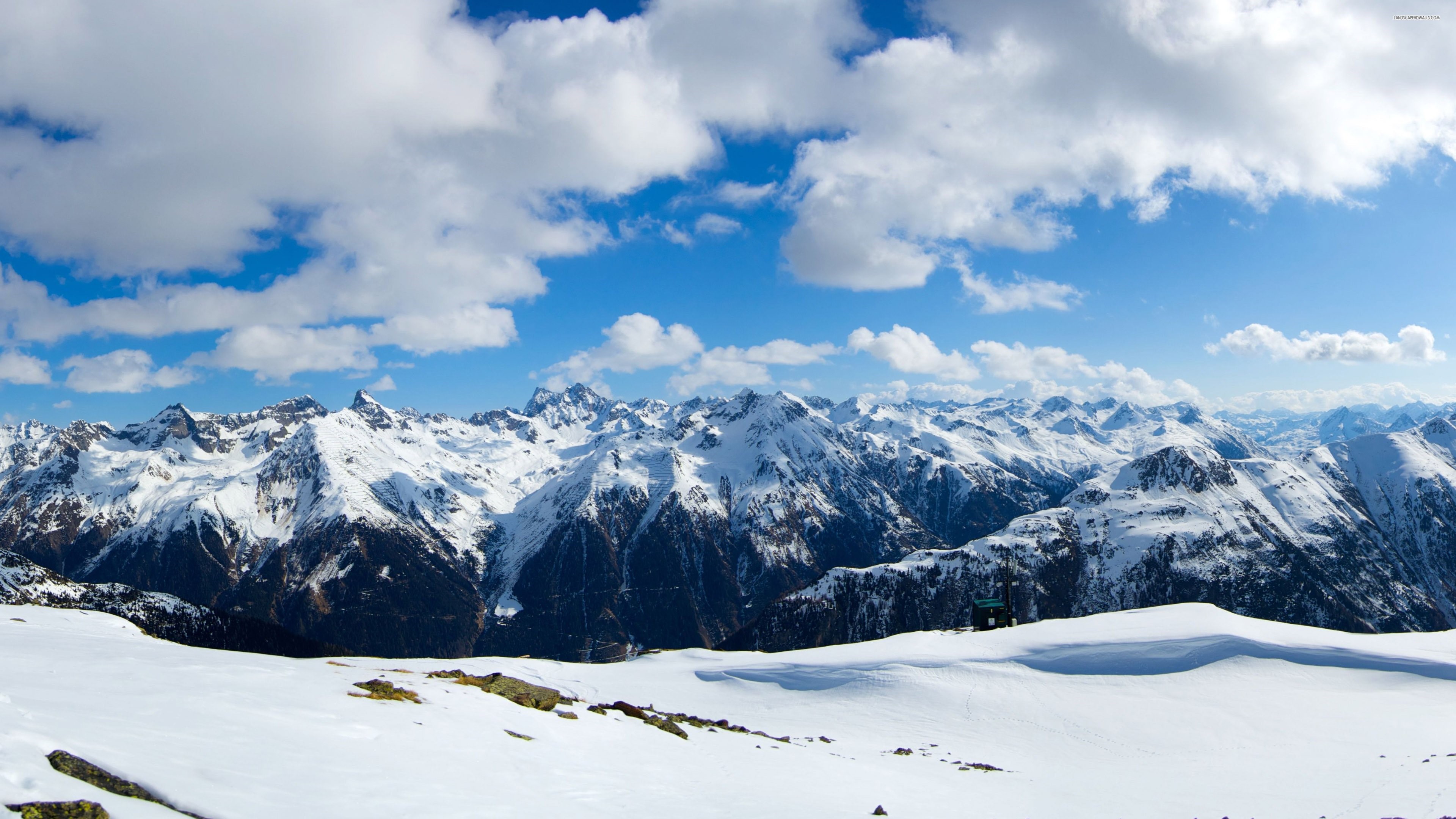 Snowy mountain range under a cloudy blue sky HD Wallpaper