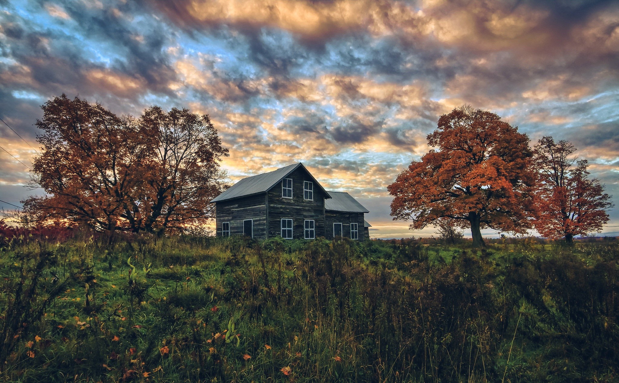 Old house on a hill with autumn trees and dramatic sky HD Wallpaper