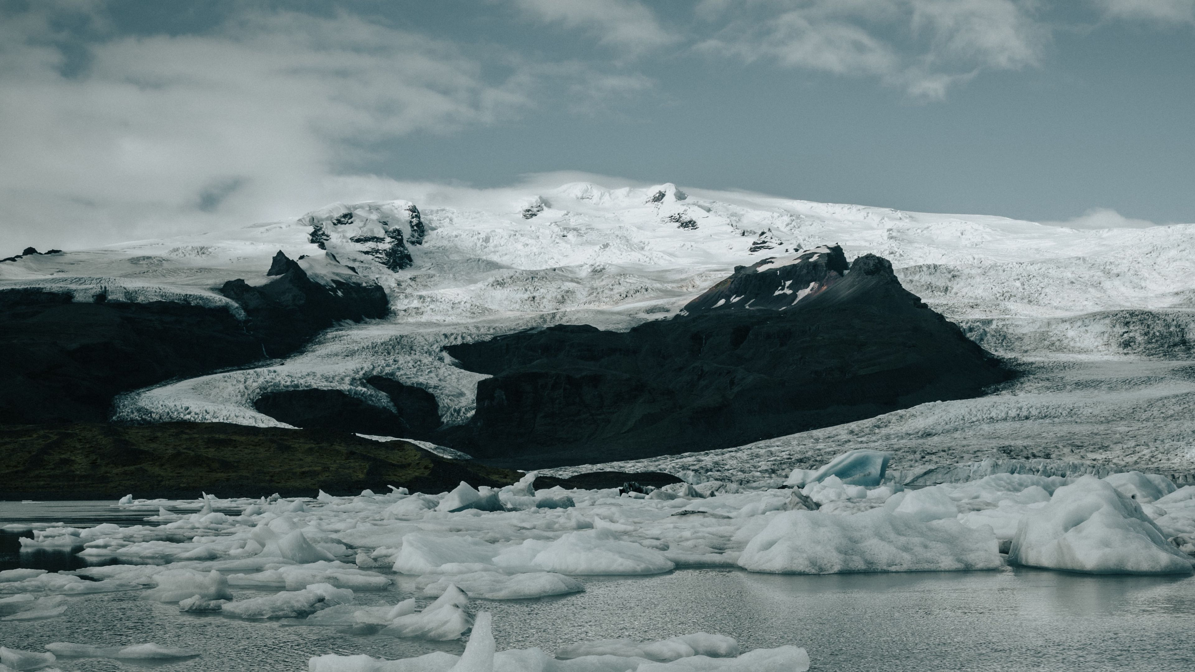 Snow-covered mountain and icebergs on a lake HD Wallpaper