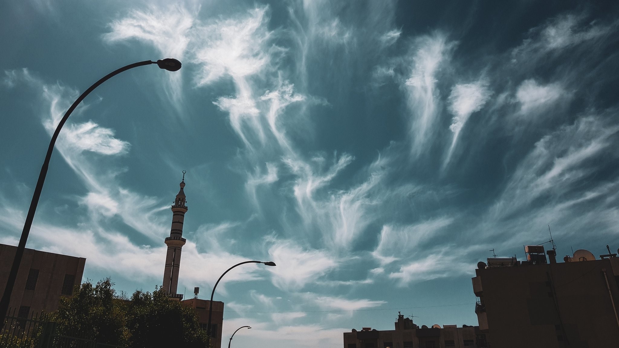 Mosque minaret and streetlights against a cloudy sky HD Wallpaper