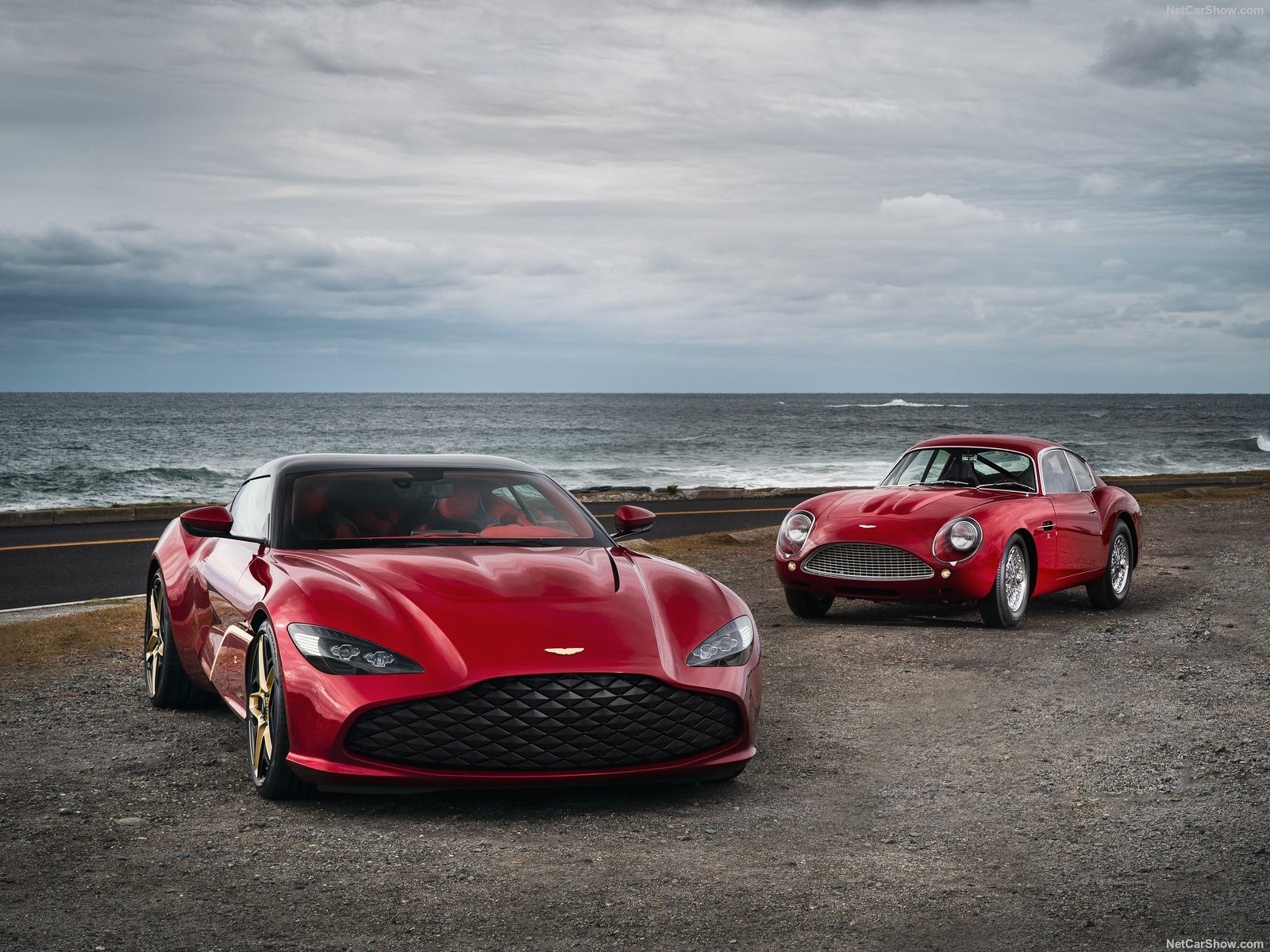 Two red Aston Martin cars by the sea HD Wallpaper
