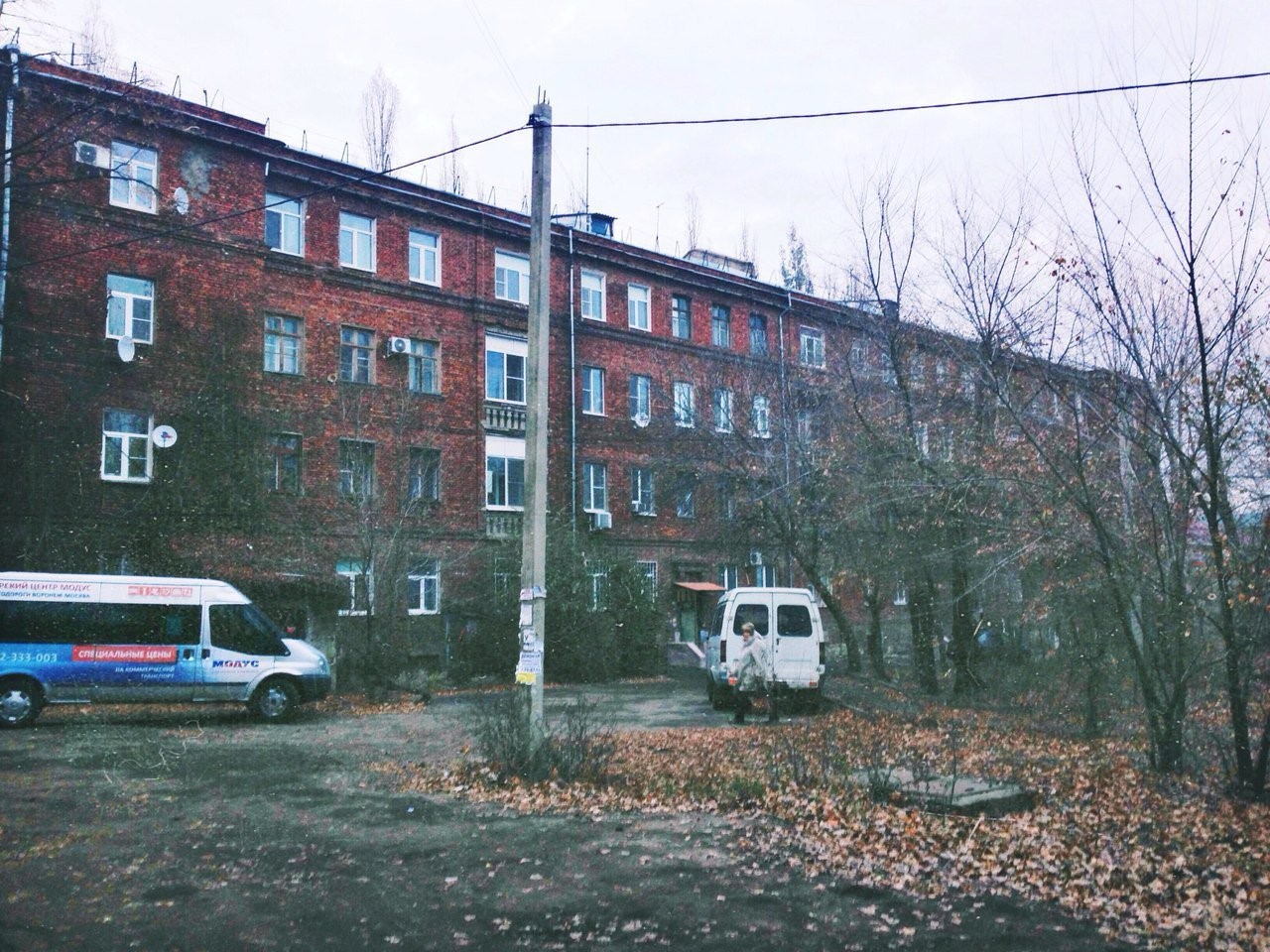 Brick apartment building with vans and bare trees HD Wallpaper