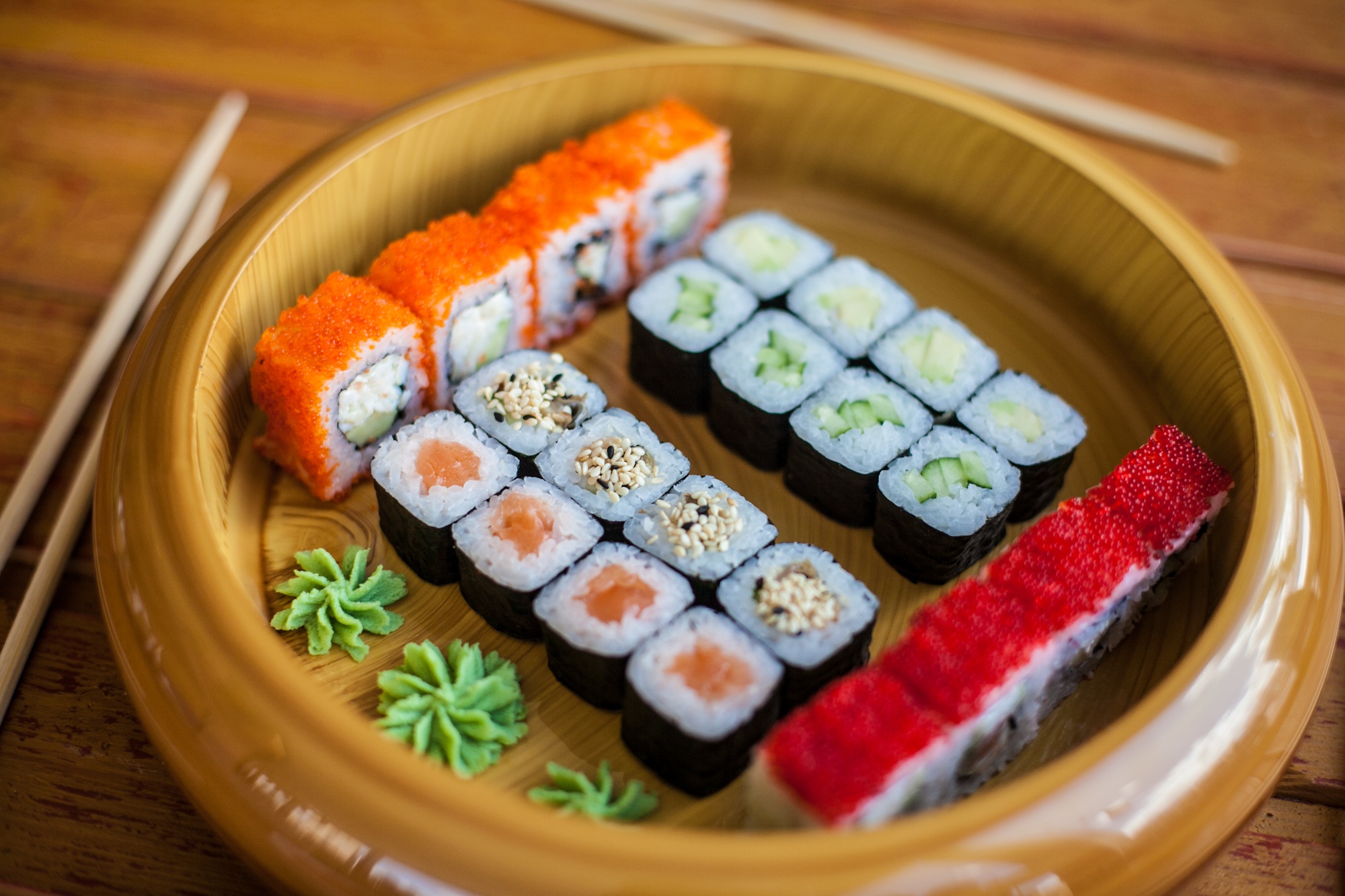 Assortment of sushi rolls on a wooden plate HD Wallpaper
