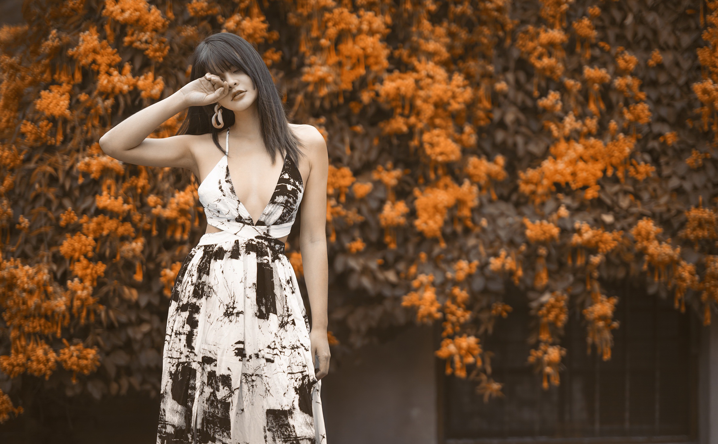 Asian woman in a patterned dress poses near orange flowers HD Wallpaper