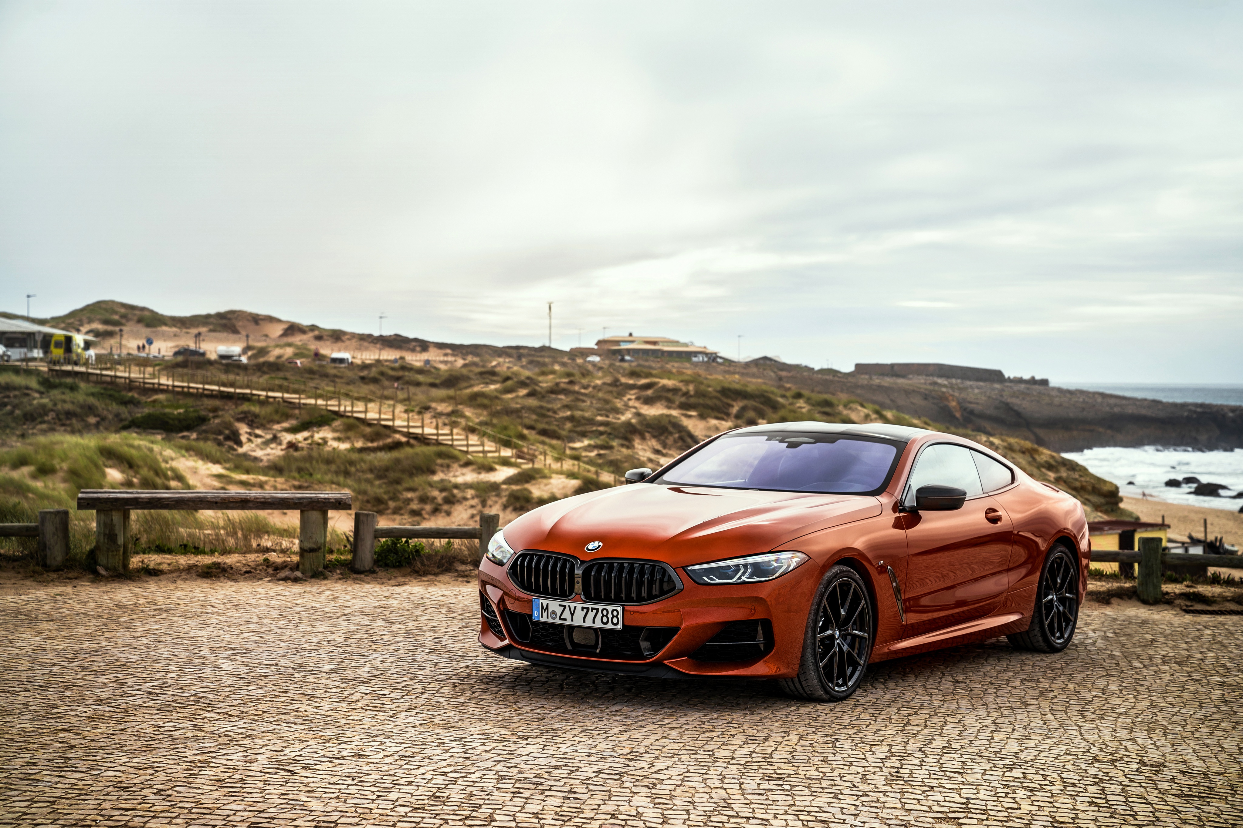 Orange BMW 8 Series Coupe on a Cobblestone Surface HD Wallpaper