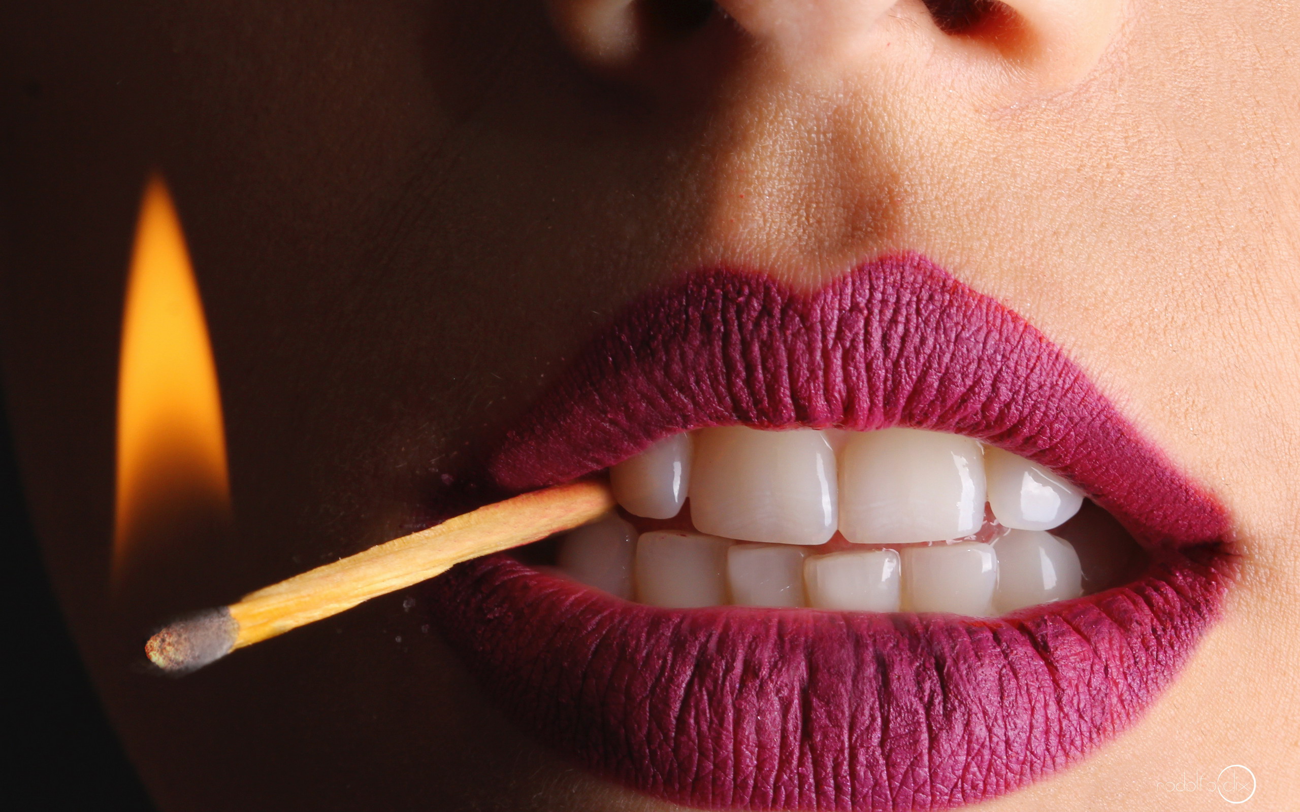 Woman biting a lit matchstick HD Wallpaper