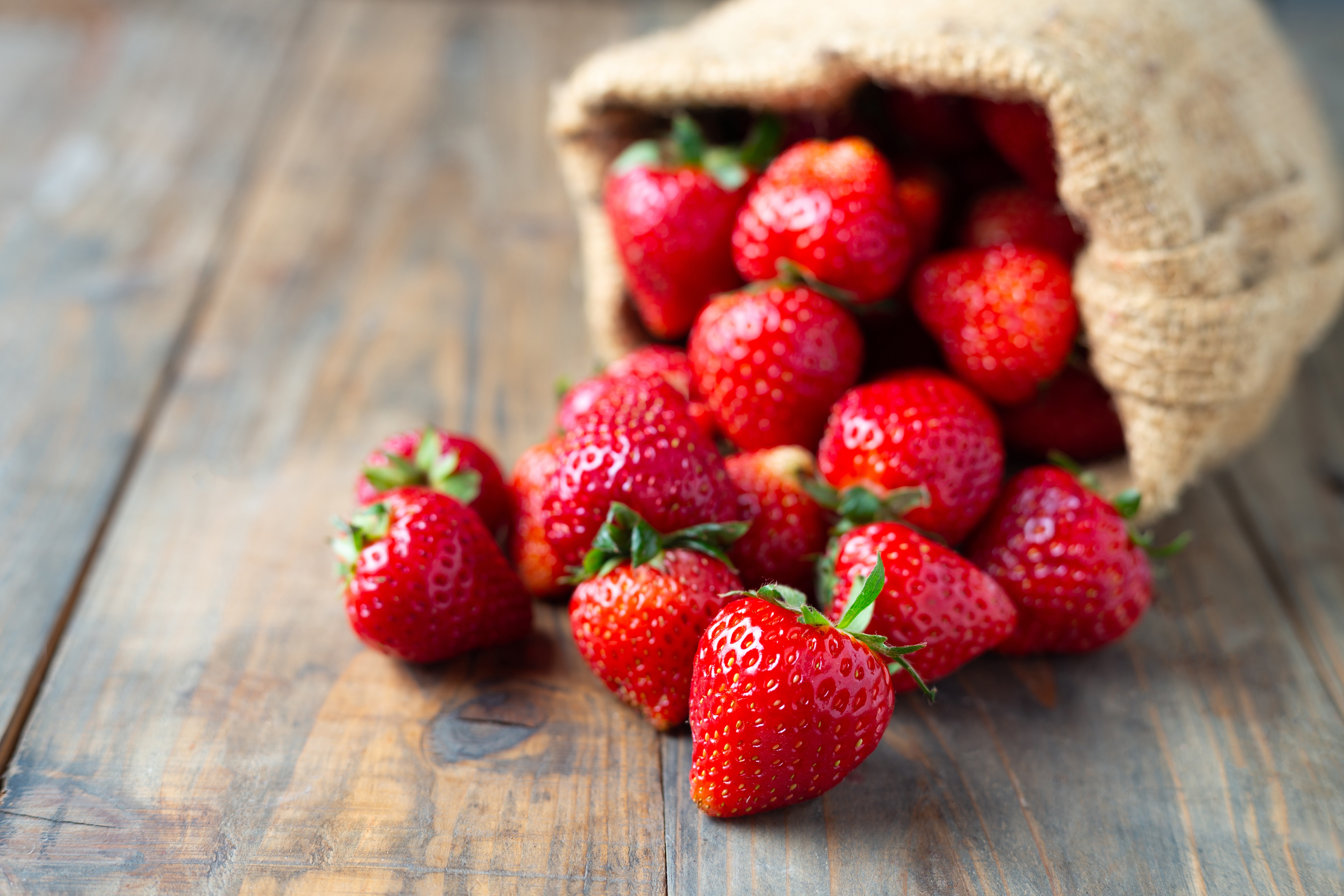Strawberries spilling from a burlap sack HD Wallpaper