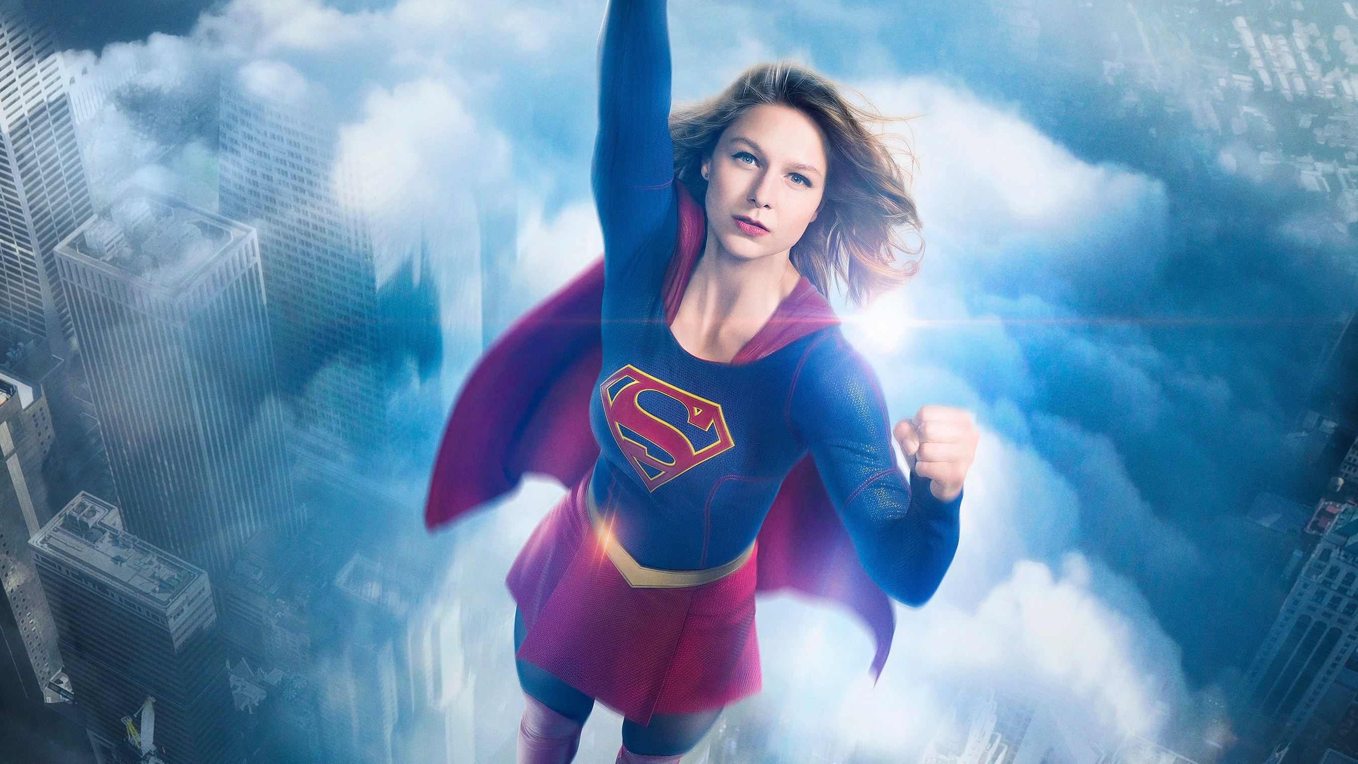 Supergirl flying over a city HD Wallpaper
