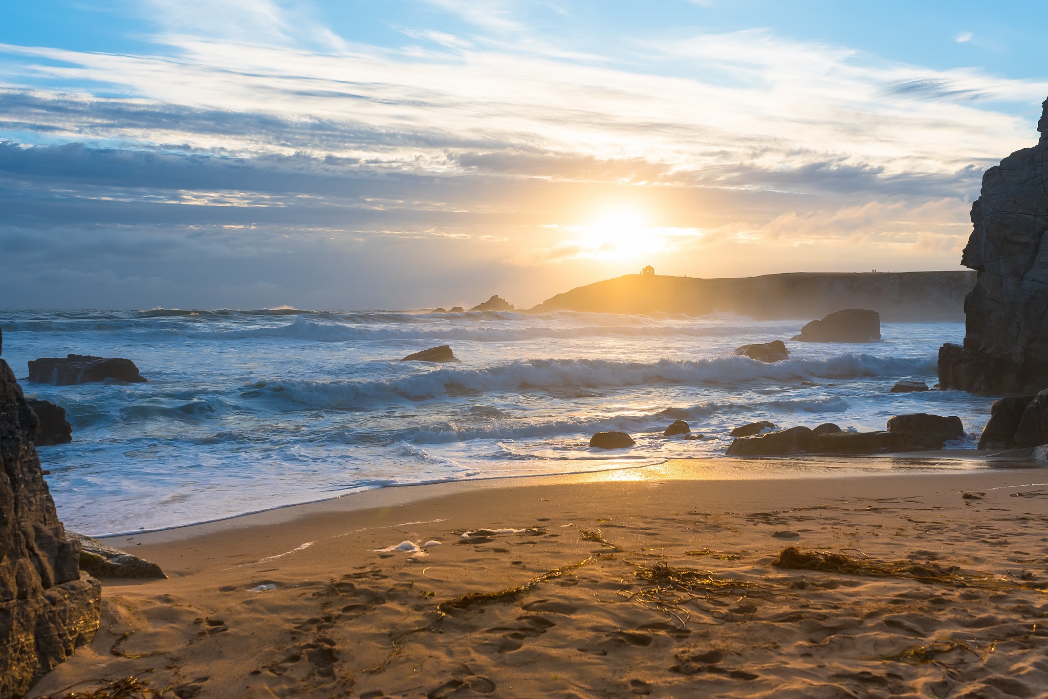 Ocean waves crash on a rocky beach at sunset HD Wallpaper