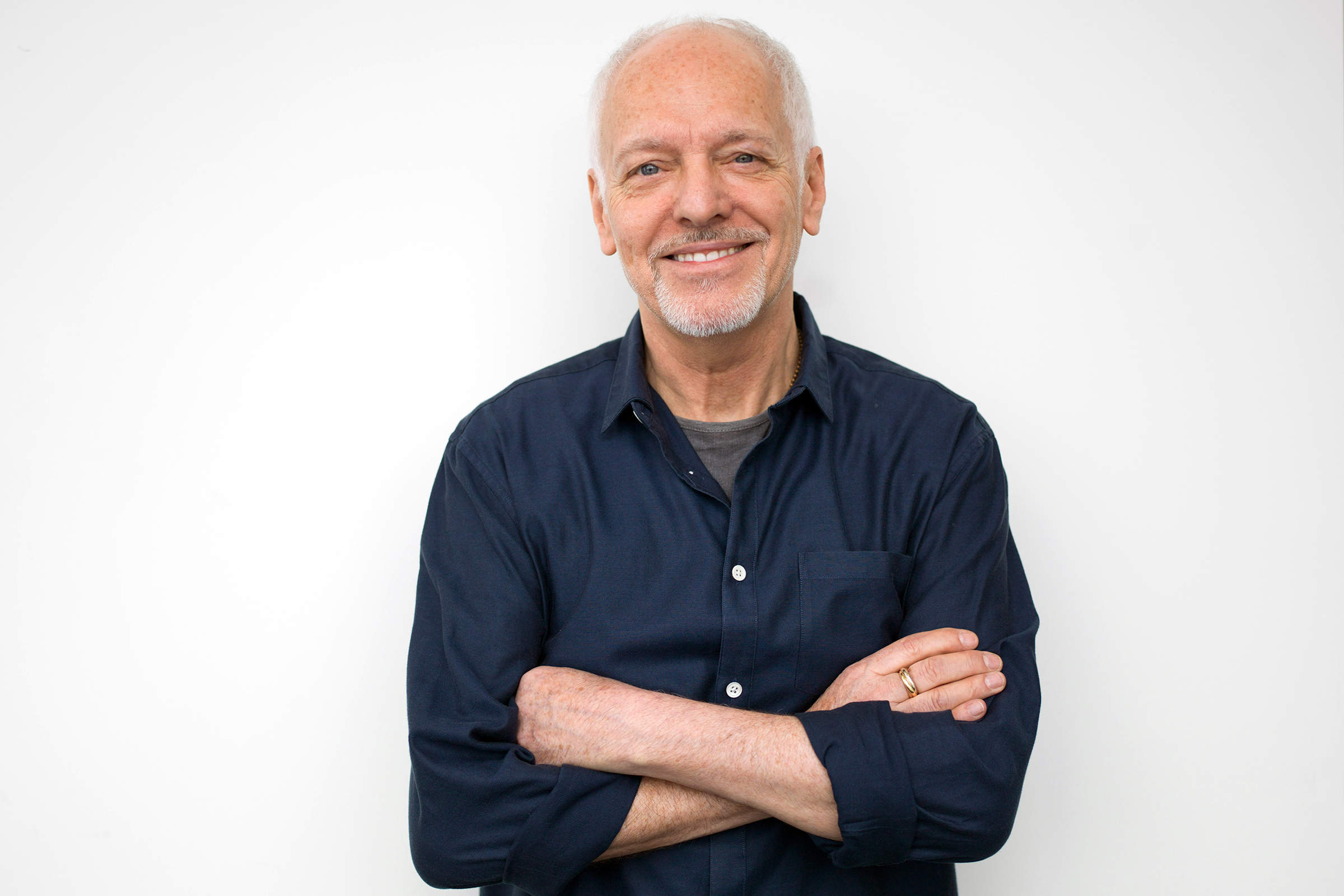 Peter Frampton smiling with arms crossed HD Wallpaper