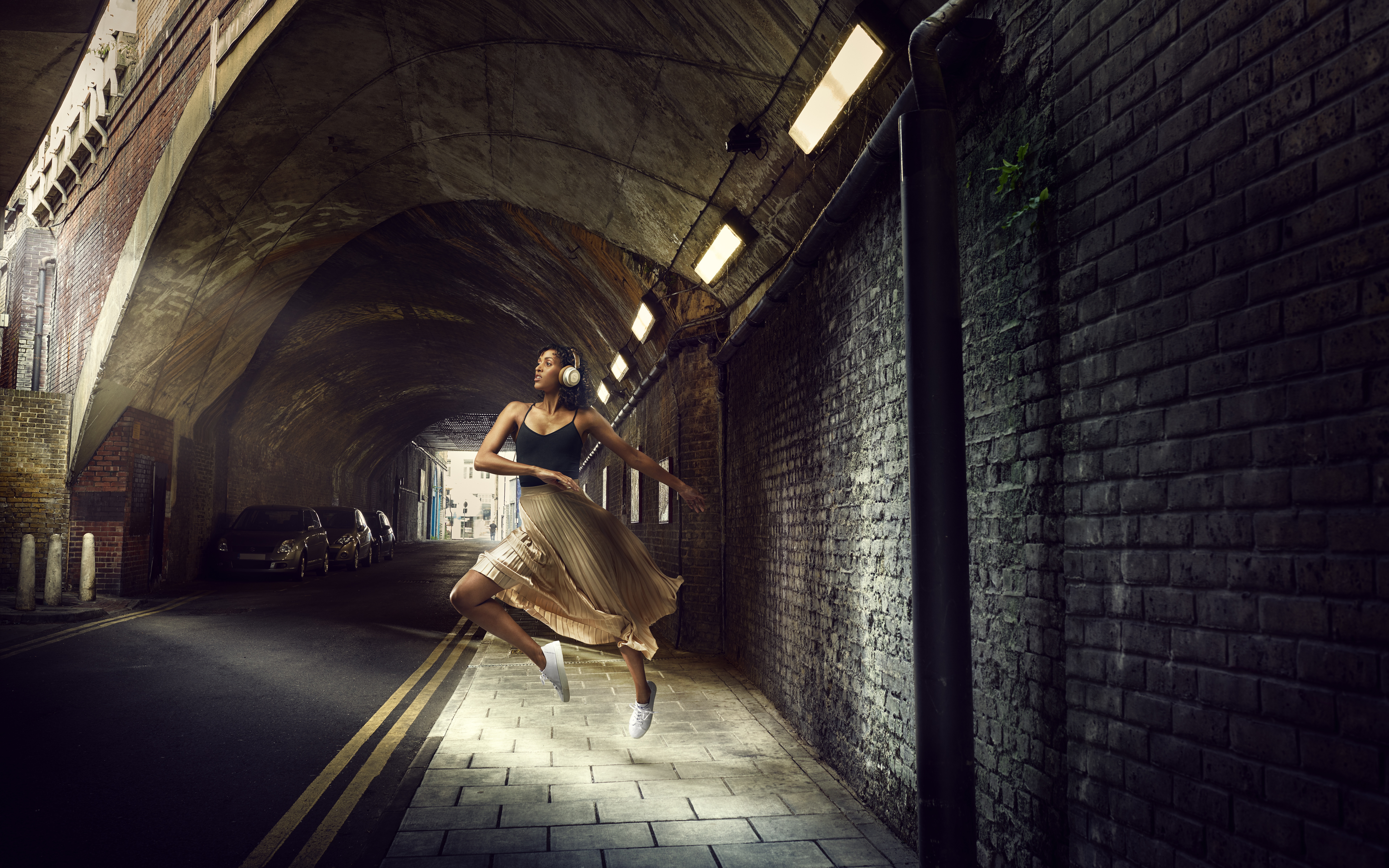 Woman with headphones dancing in a tunnel HD Wallpaper
