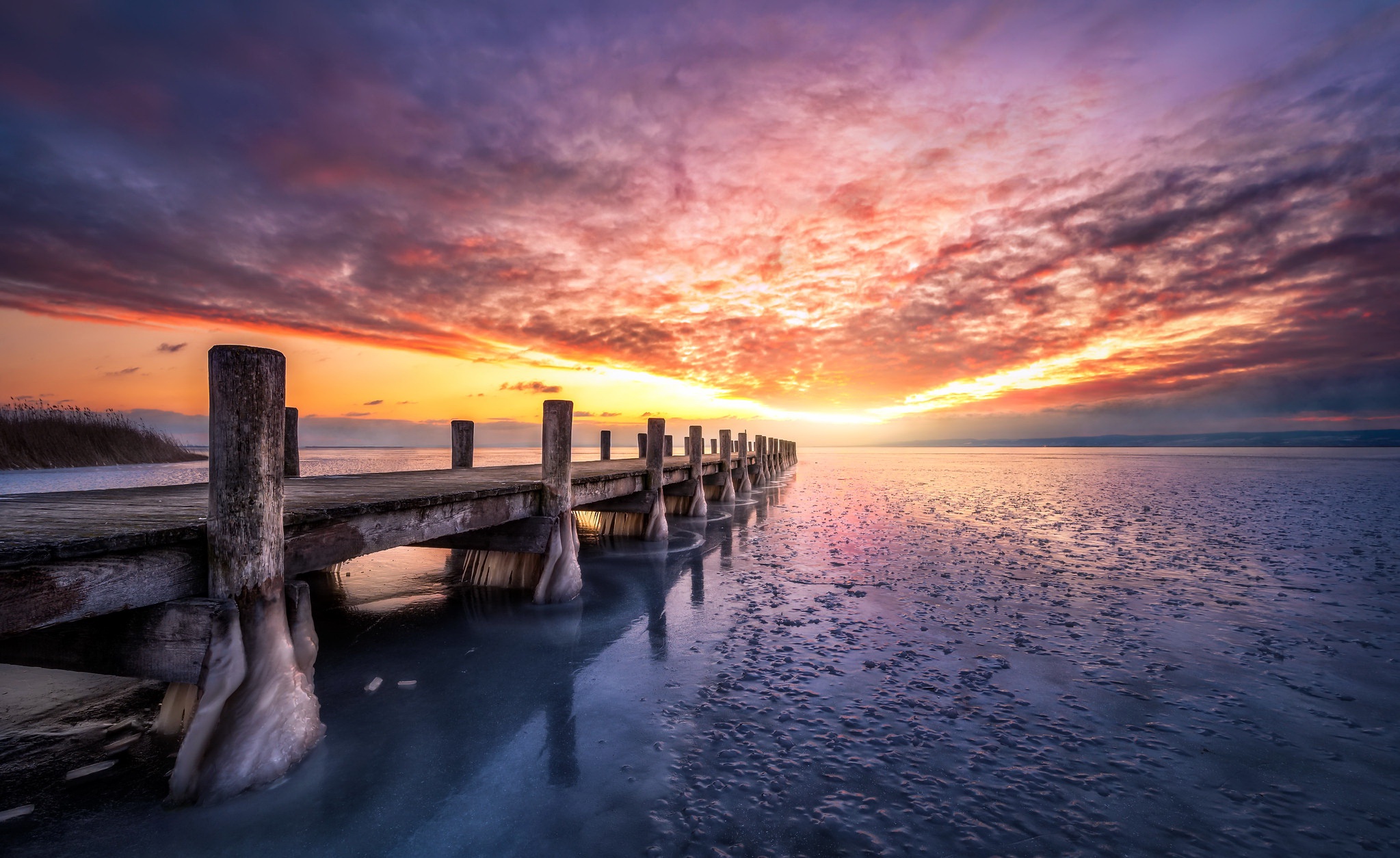 Wooden pier on a frozen lake at sunset HD Wallpaper