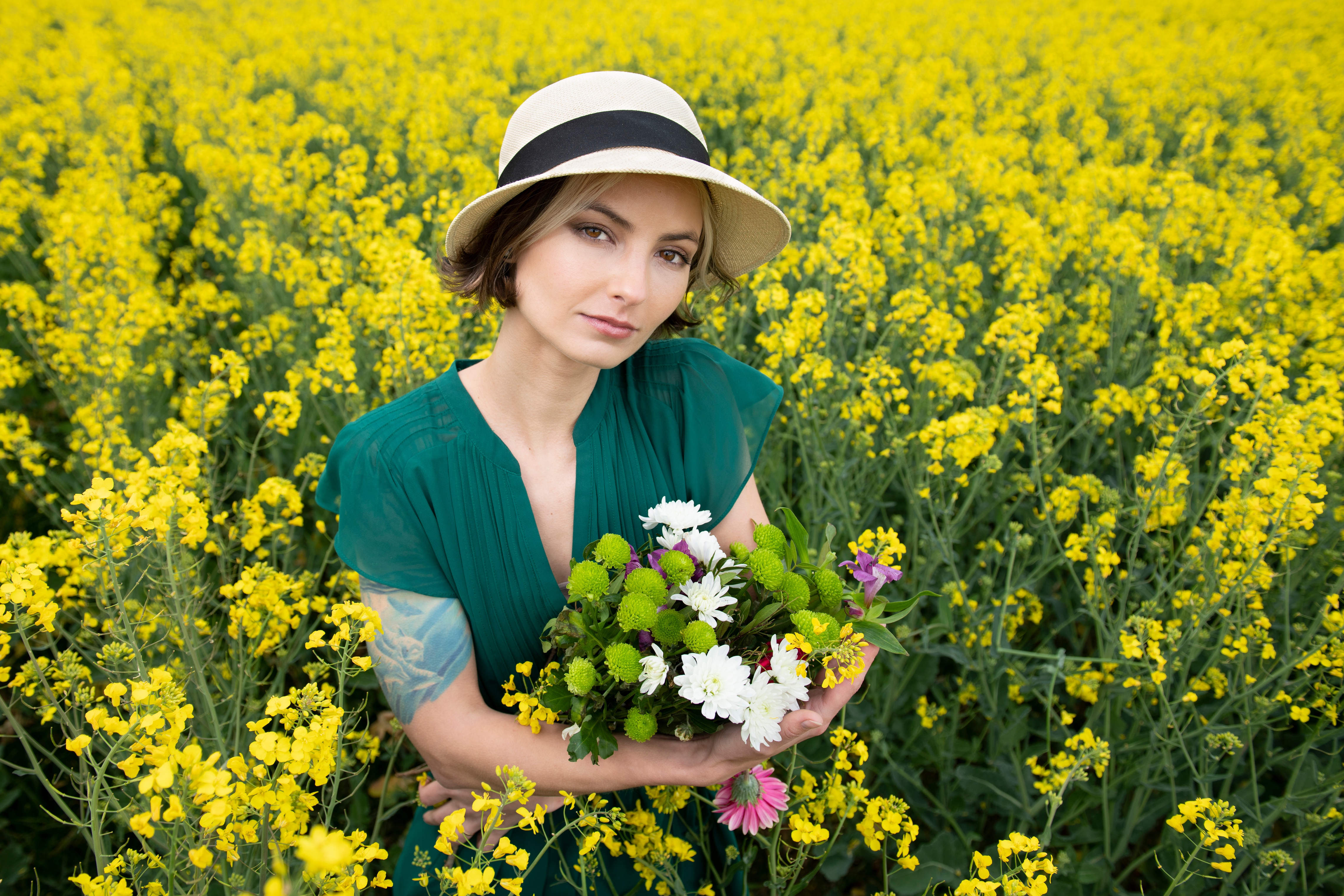 Woman in Hat Holding Flowers in Rapeseed Field HD Wallpaper