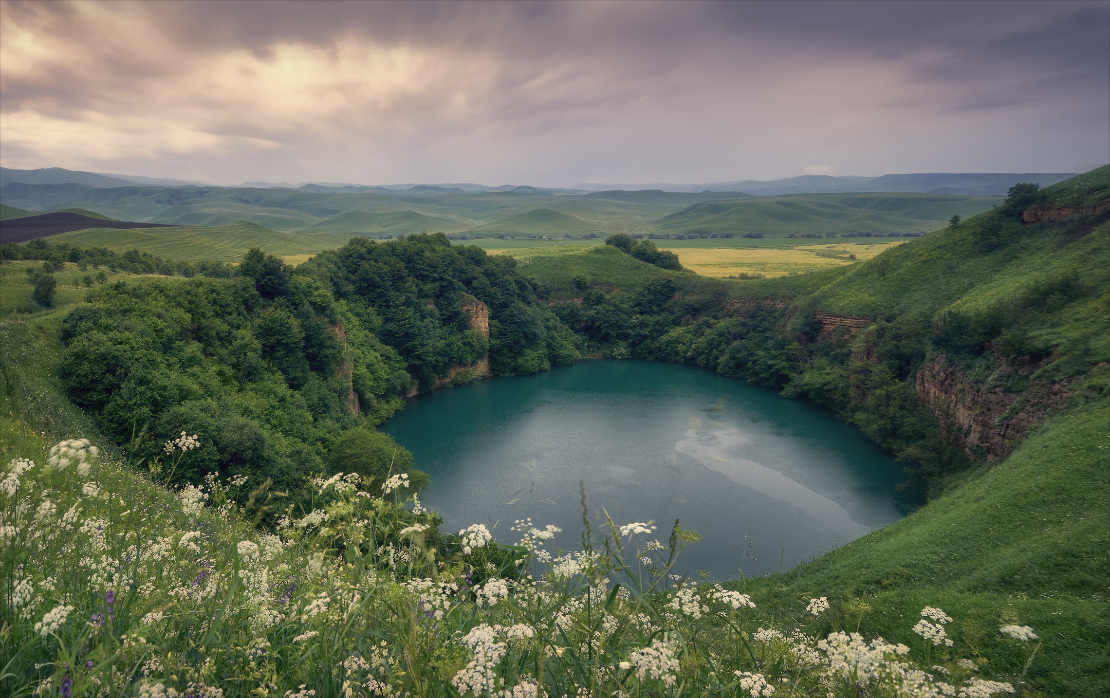 Turquoise lake surrounded by green hills and trees HD Wallpaper