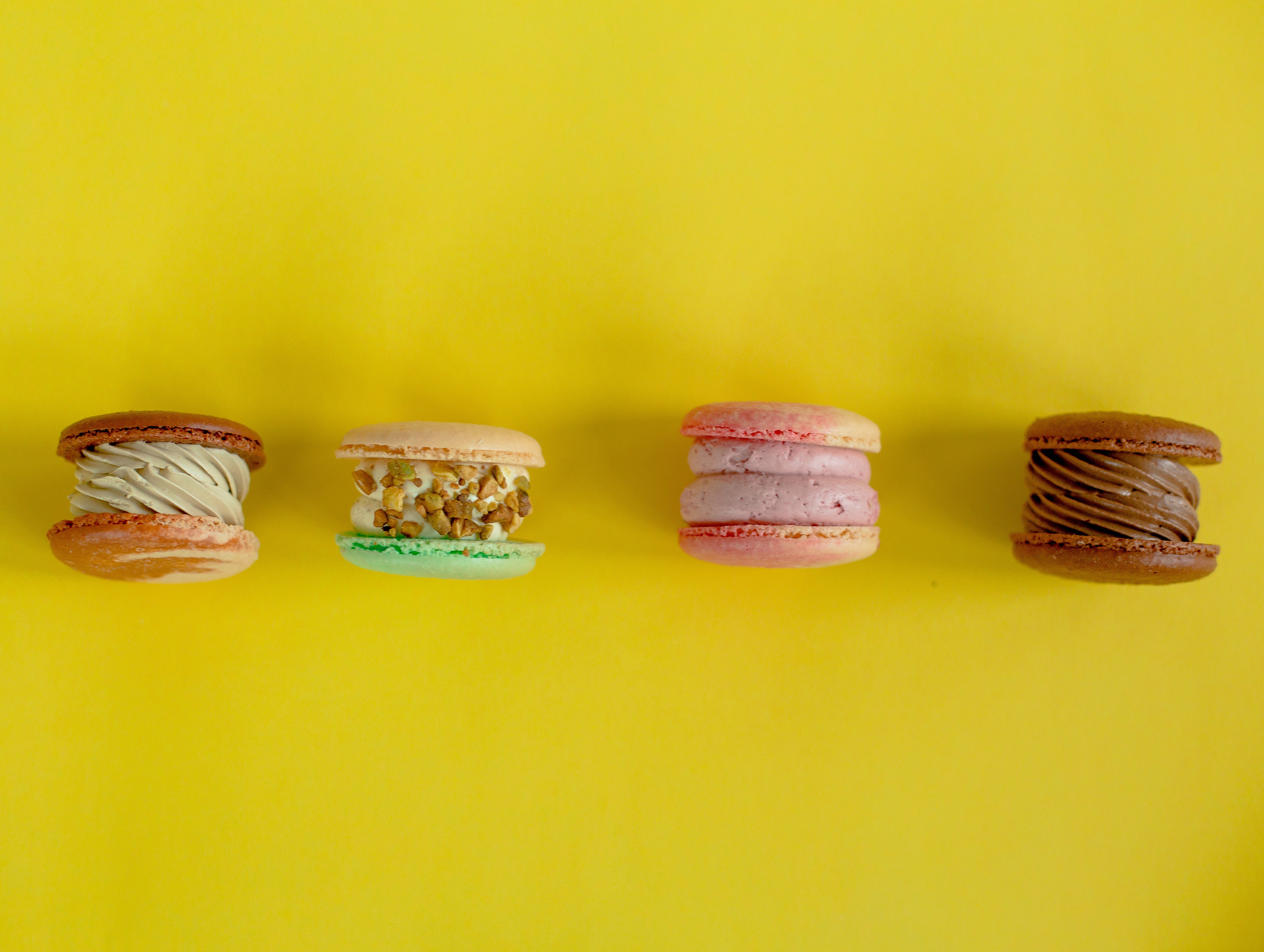 Four colorful macarons on a yellow background HD Wallpaper