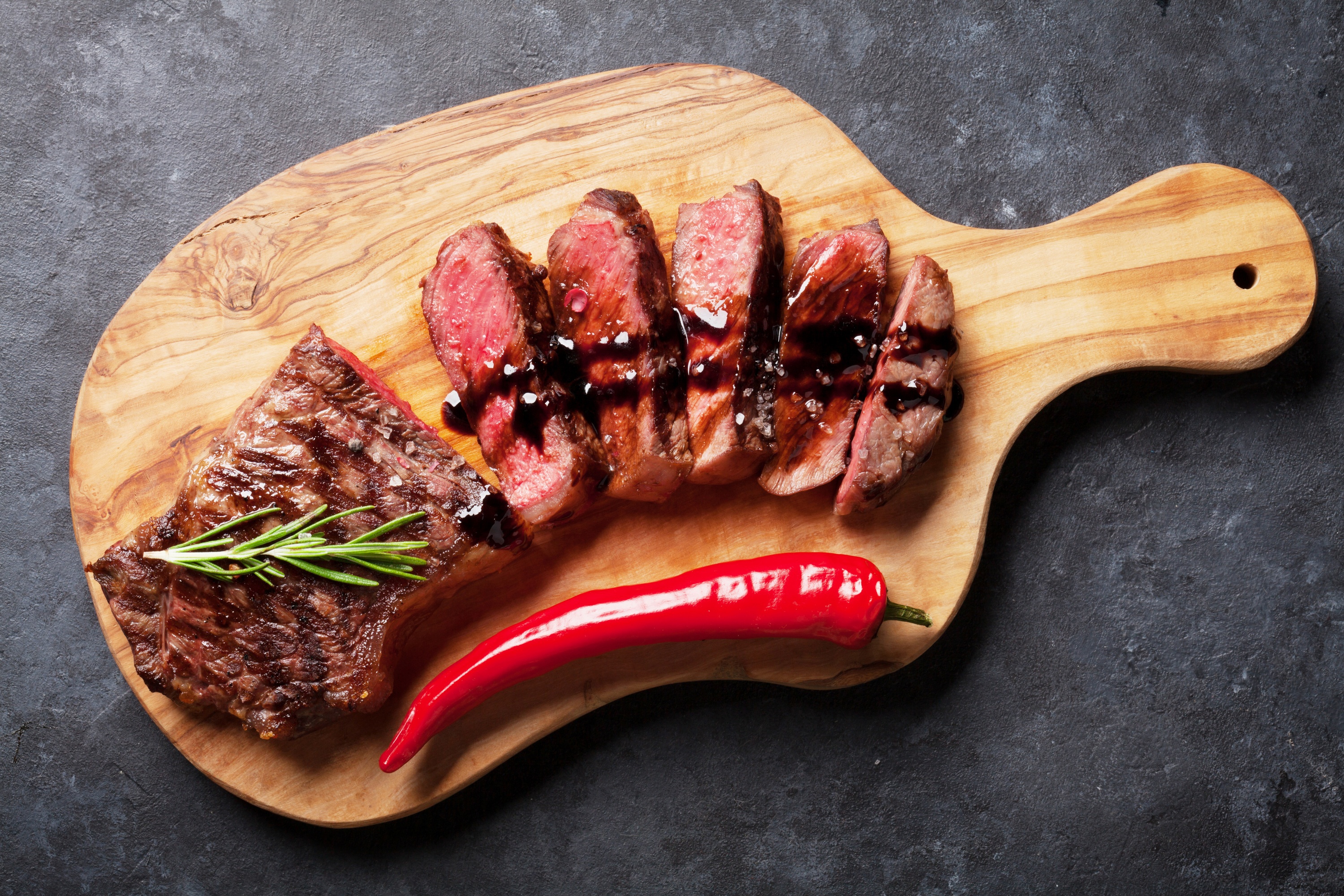Sliced steak with chili pepper on a wooden board HD Wallpaper