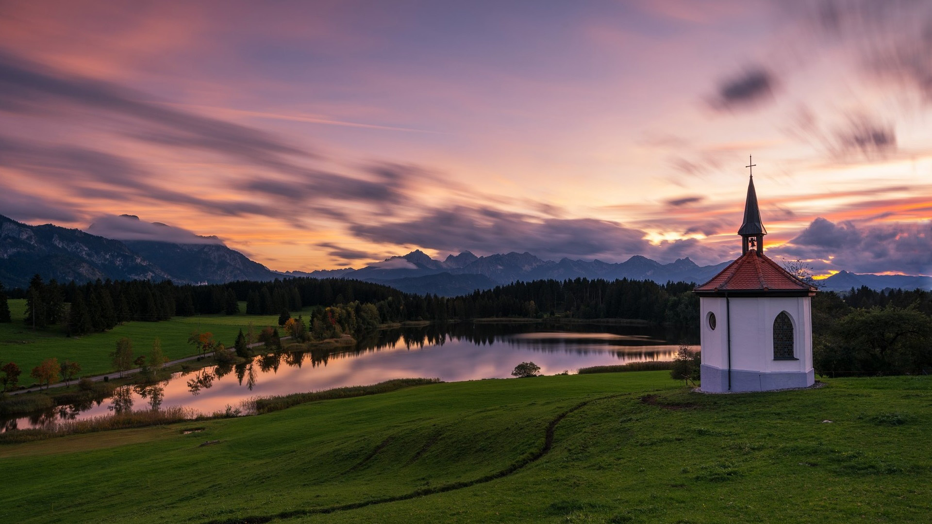 Chapel by a lake at sunset with mountains HD Wallpaper