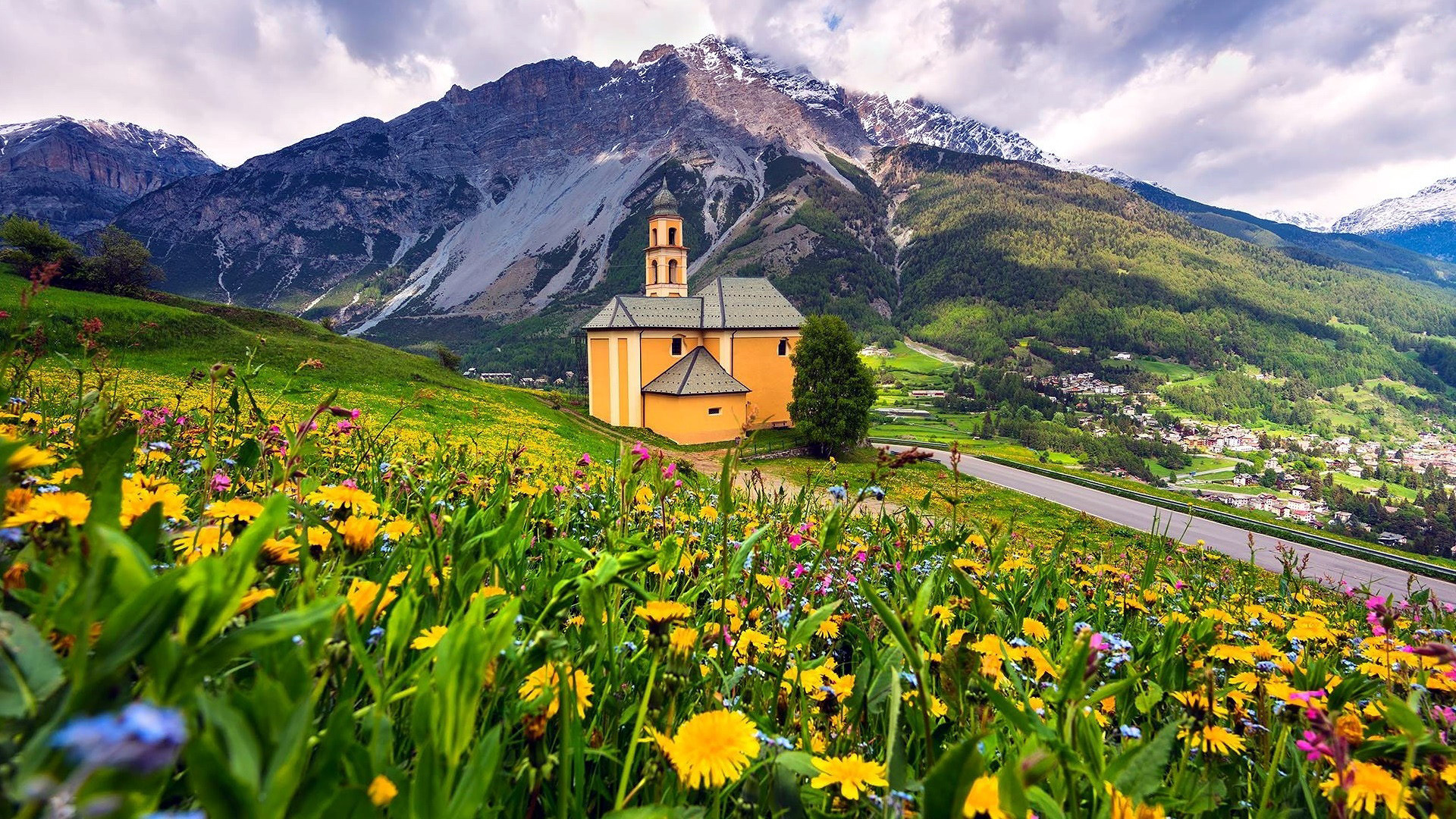 Yellow church in a mountain landscape with wildflowers HD Wallpaper