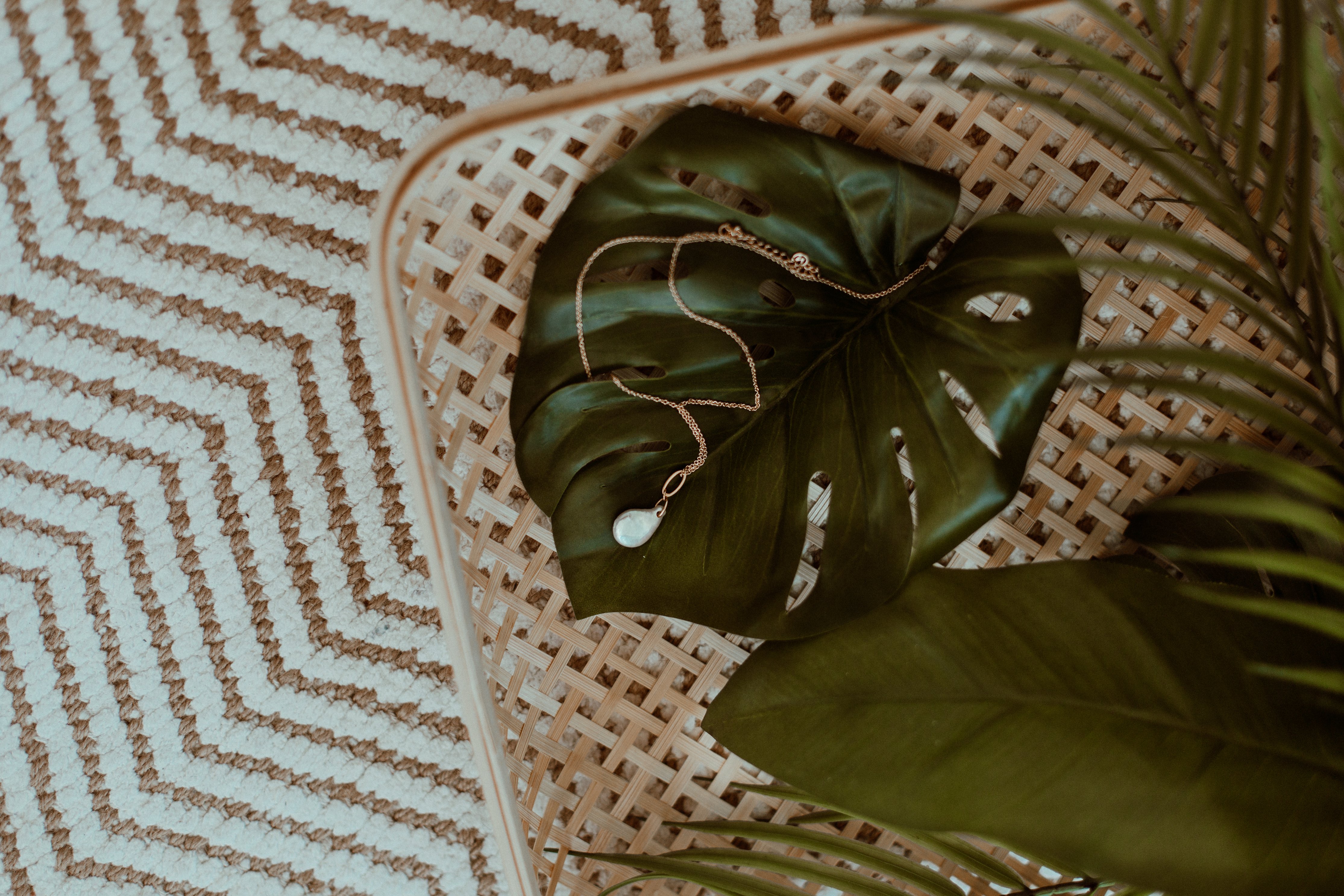 Necklace on a Monstera leaf on a woven surface HD Wallpaper