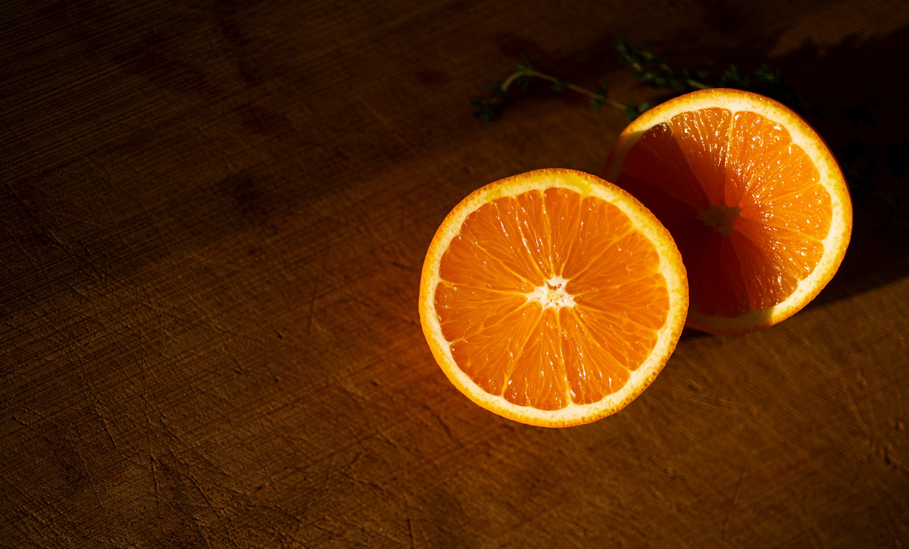 Two orange slices on a wooden cutting board HD Wallpaper