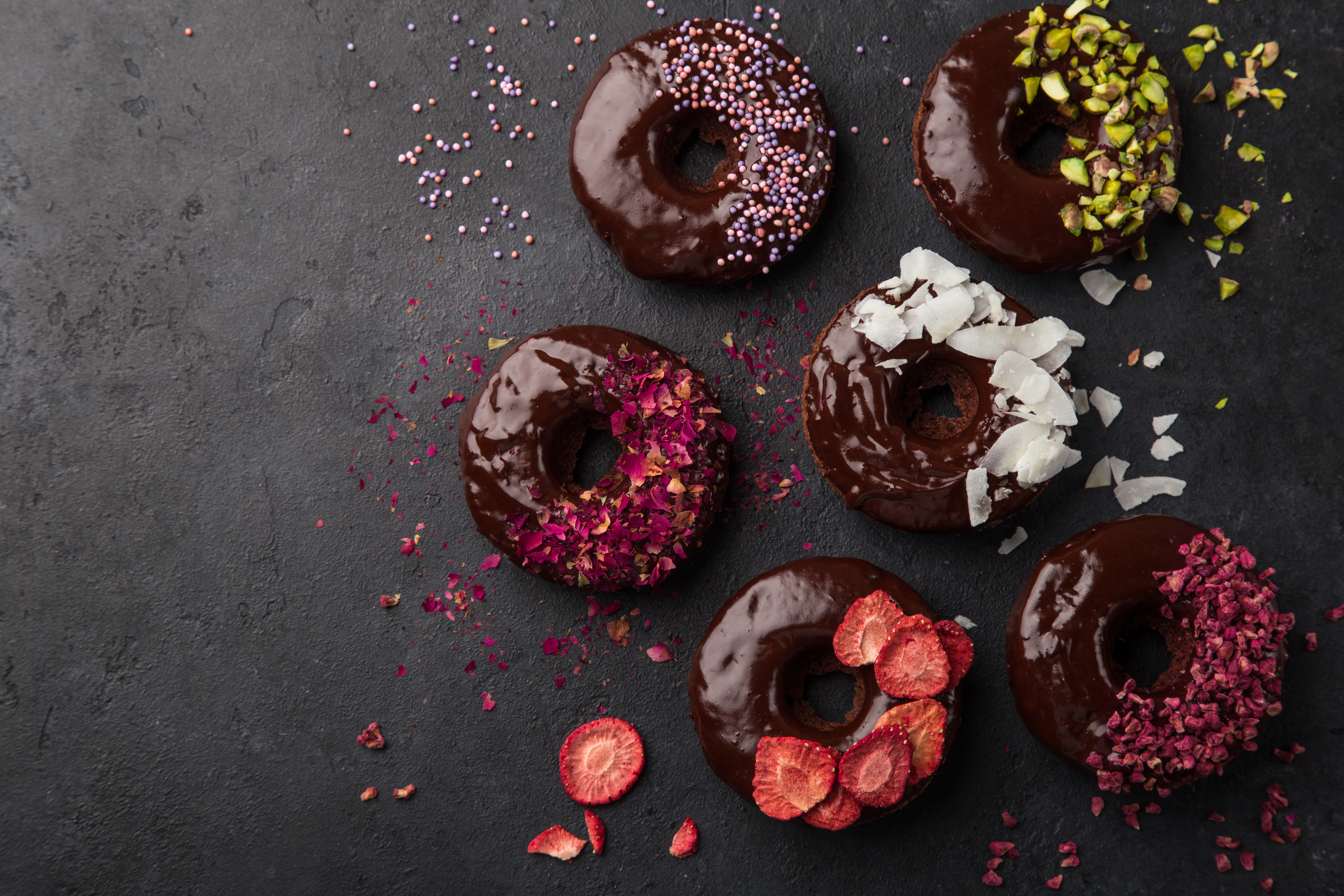 Chocolate donuts with various toppings on a dark surface HD Wallpaper
