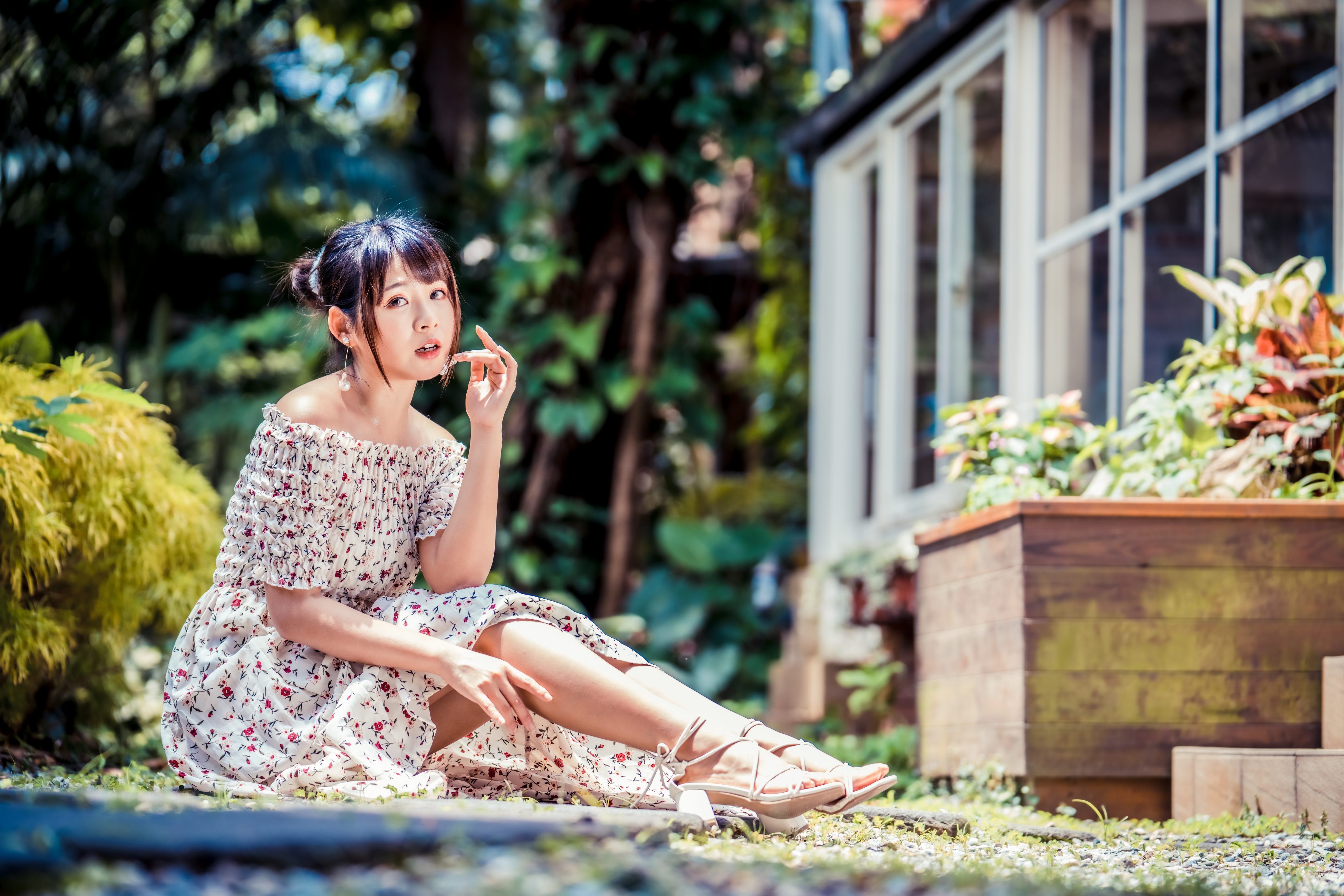 Woman in floral dress sitting in a garden HD Wallpaper
