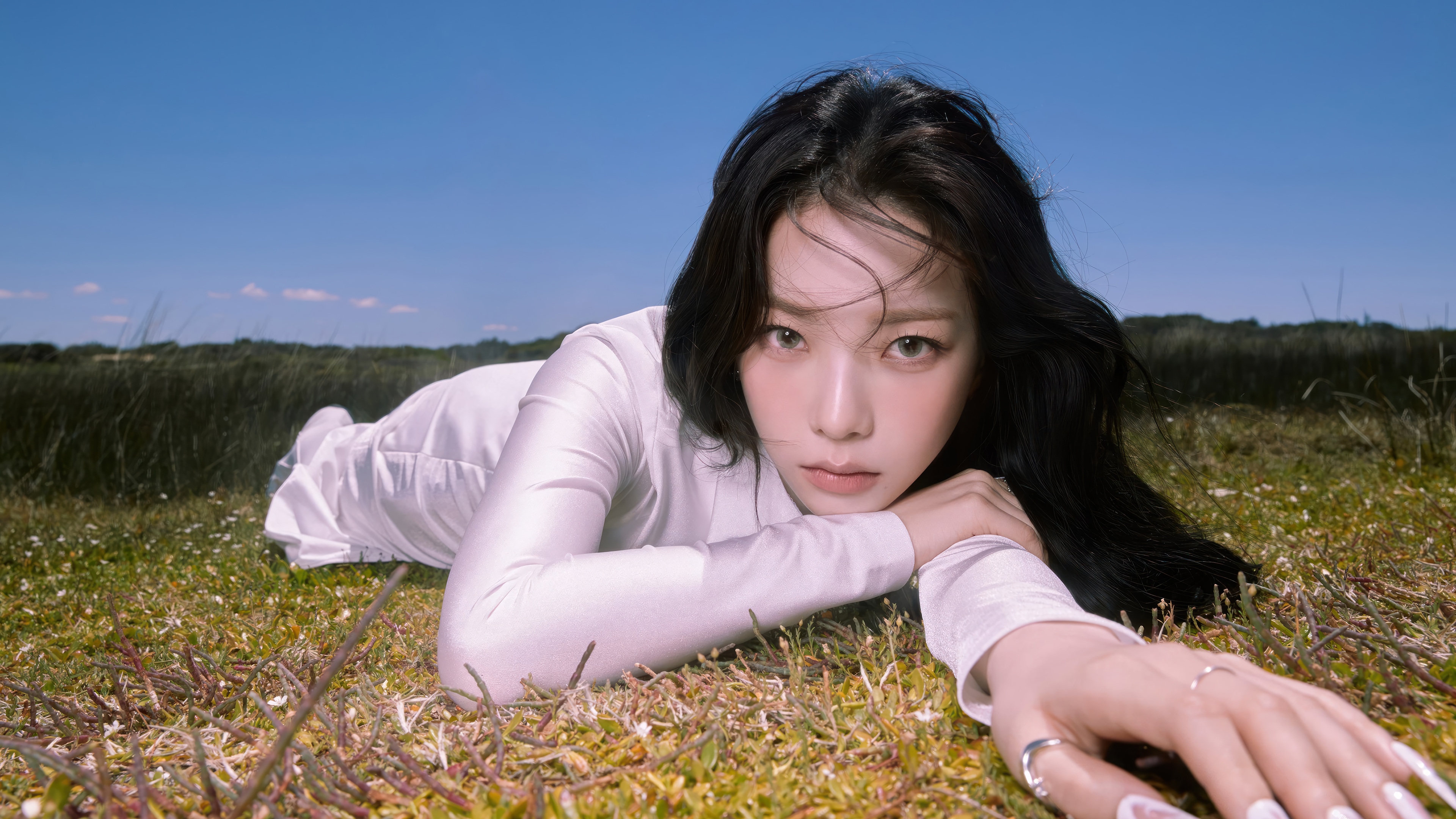 Karina from Aespa lying on grass under blue sky HD Wallpaper