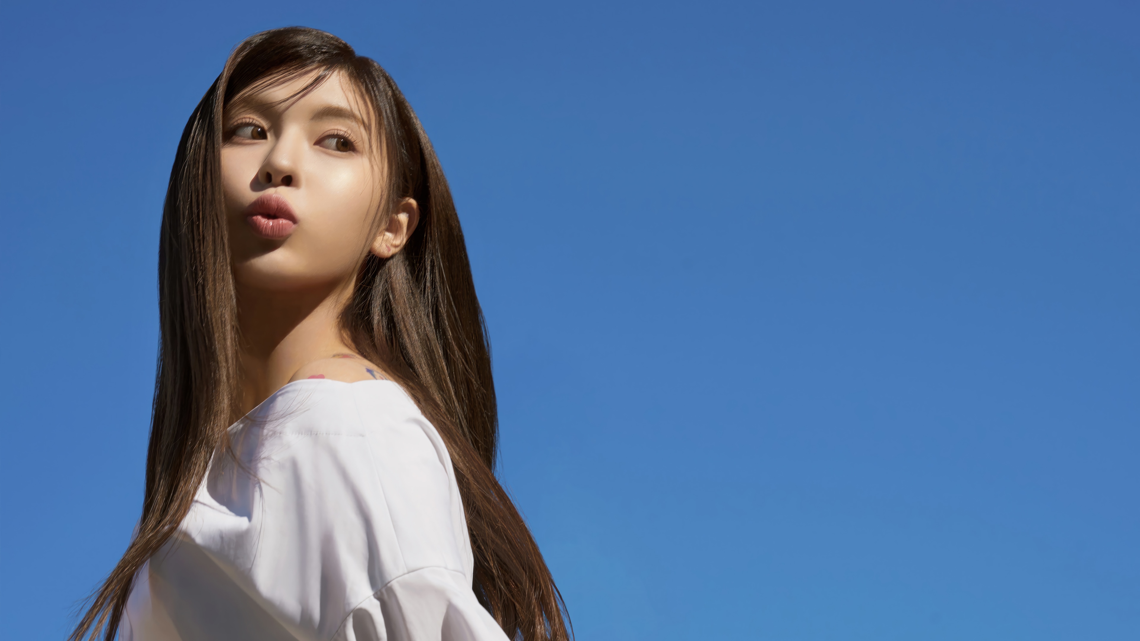 BAE from NMIXX posing against a blue sky HD Wallpaper