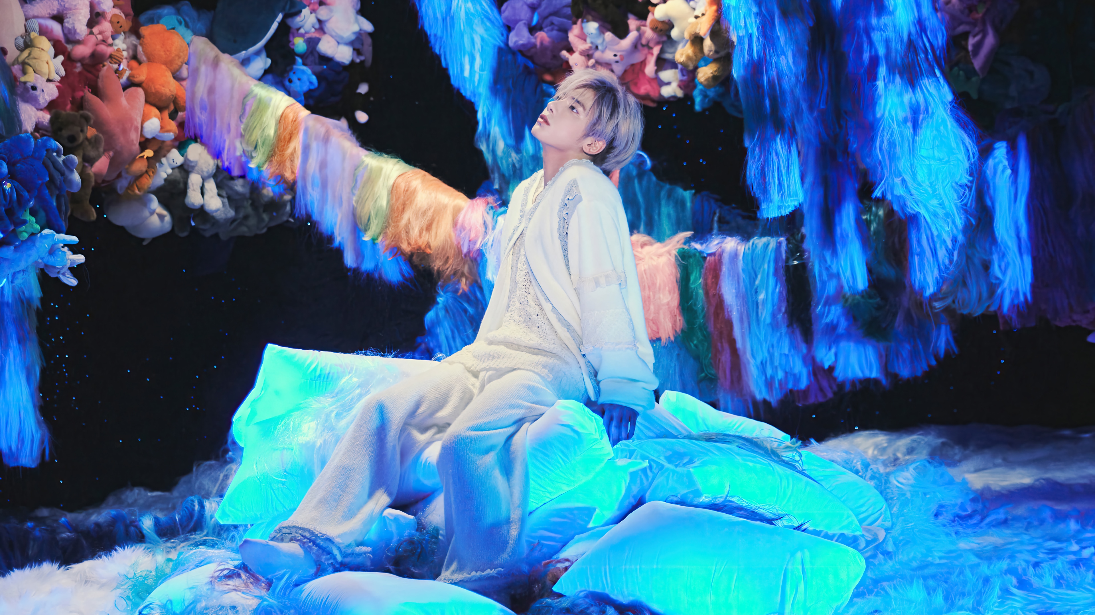 Taehyun from TXT sits on glowing pillows HD Wallpaper