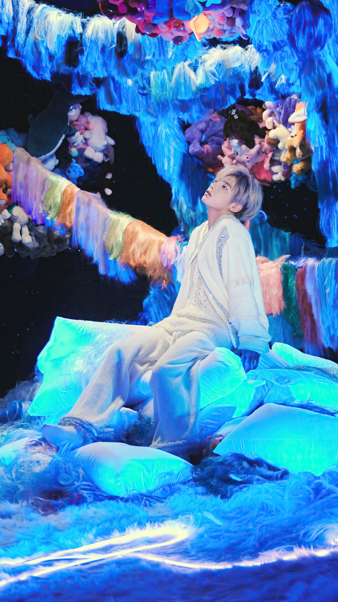 Taehyun from TXT sits on glowing blue pillows HD Phone Wallpaper