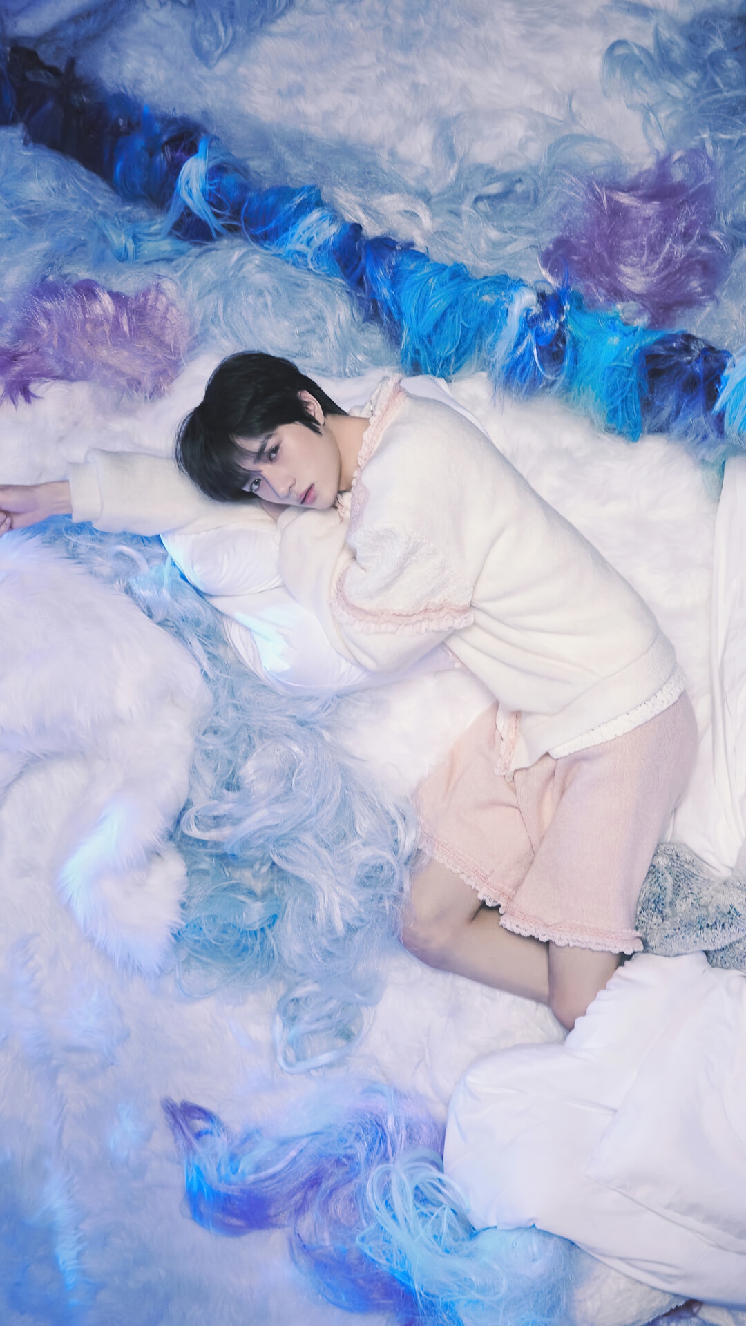 Beomgyu from TXT lying on a bed with colorful hair HD Phone Wallpaper