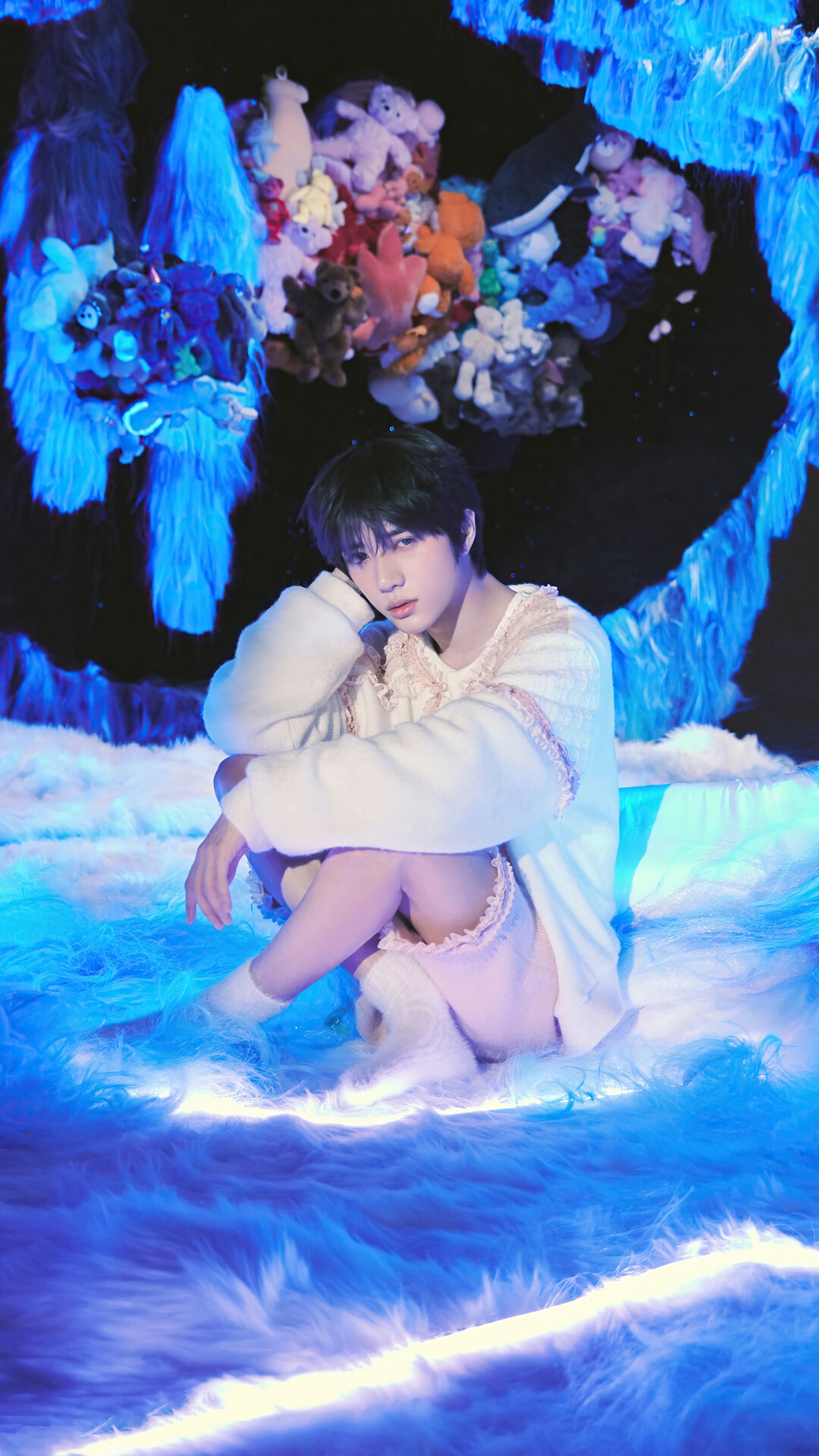 Beomgyu from TXT sitting on a fluffy blue surface HD Phone Wallpaper