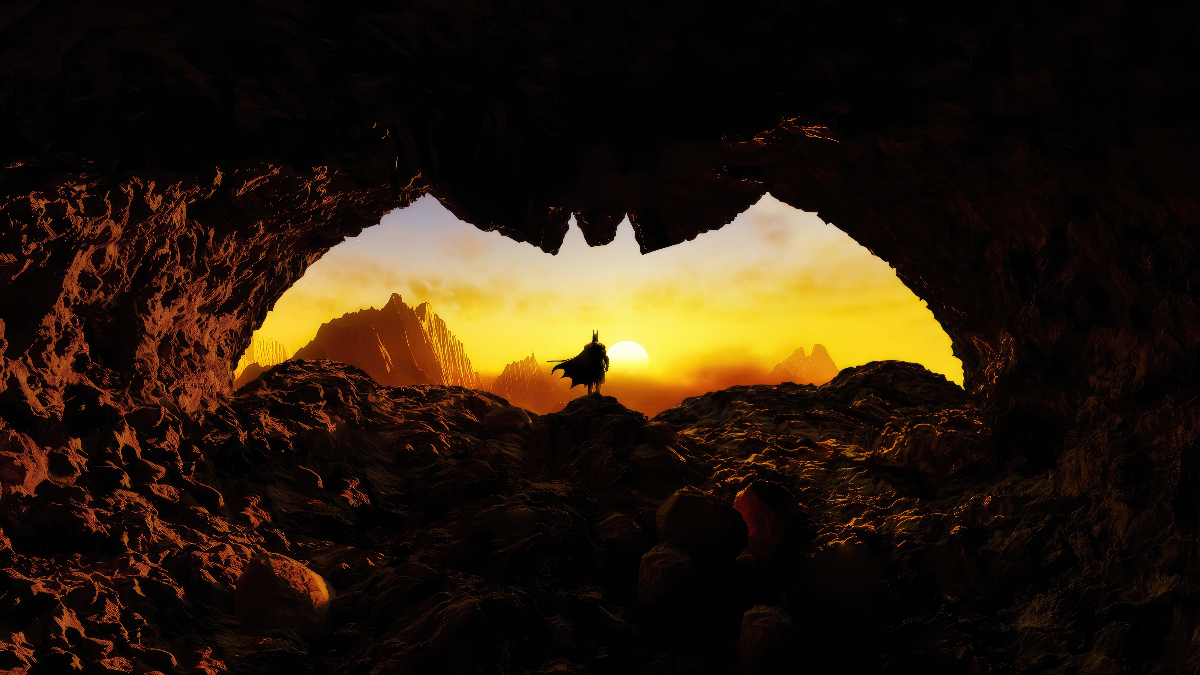 Batman standing in a cave entrance at sunset HD Wallpaper