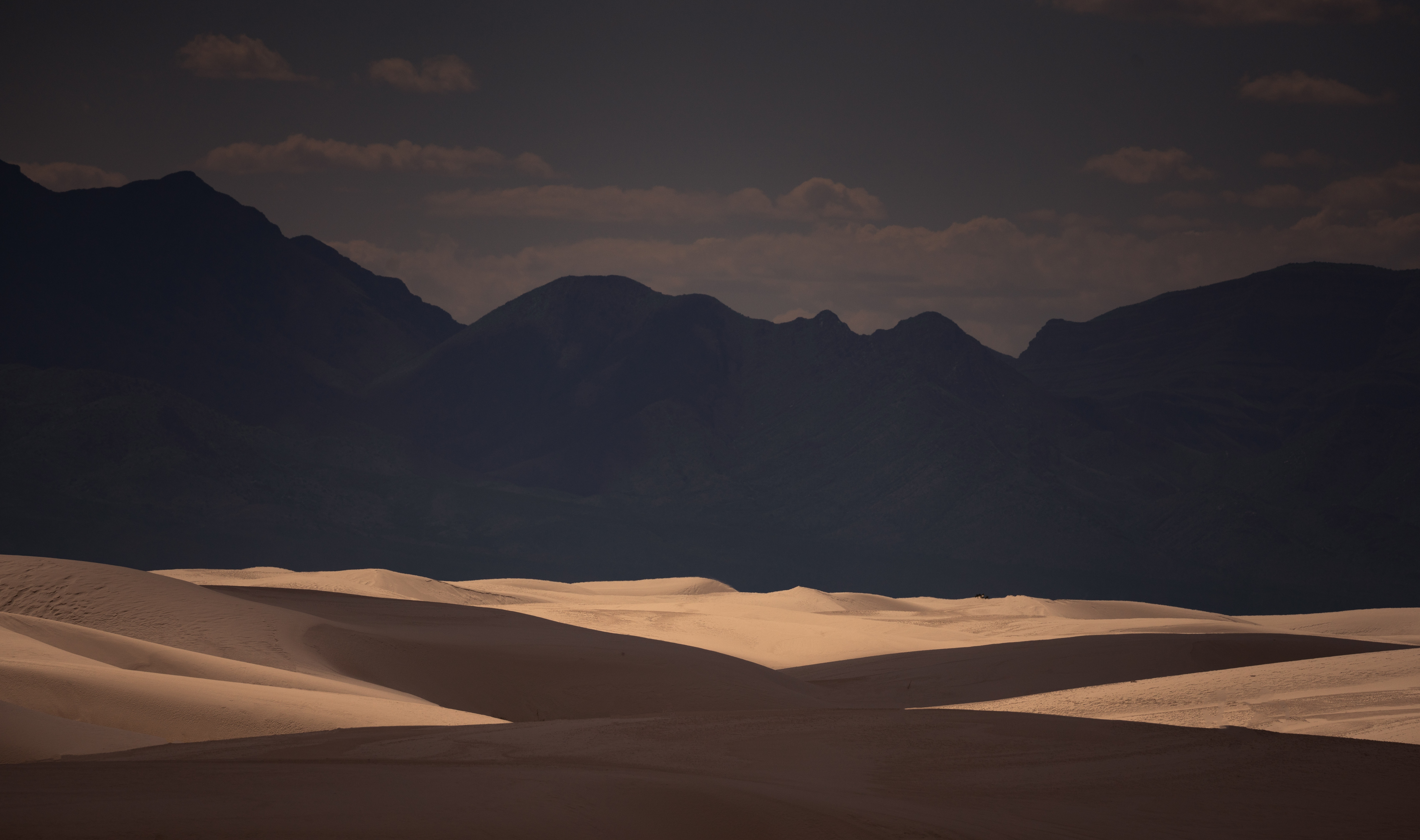 Sand dunes and mountains under a dark sky HD Wallpaper