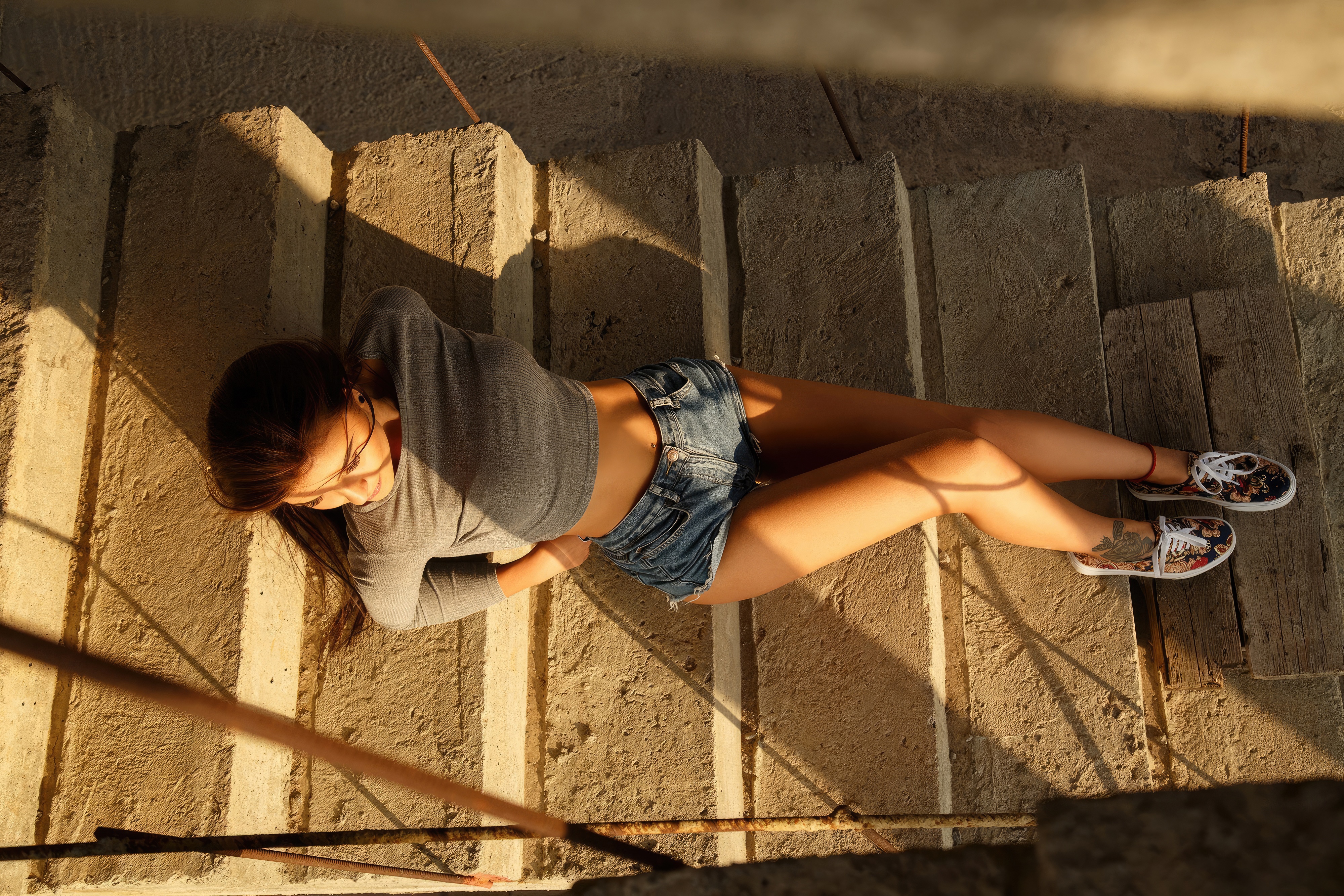 Model in denim shorts and grey top on stairs HD Wallpaper