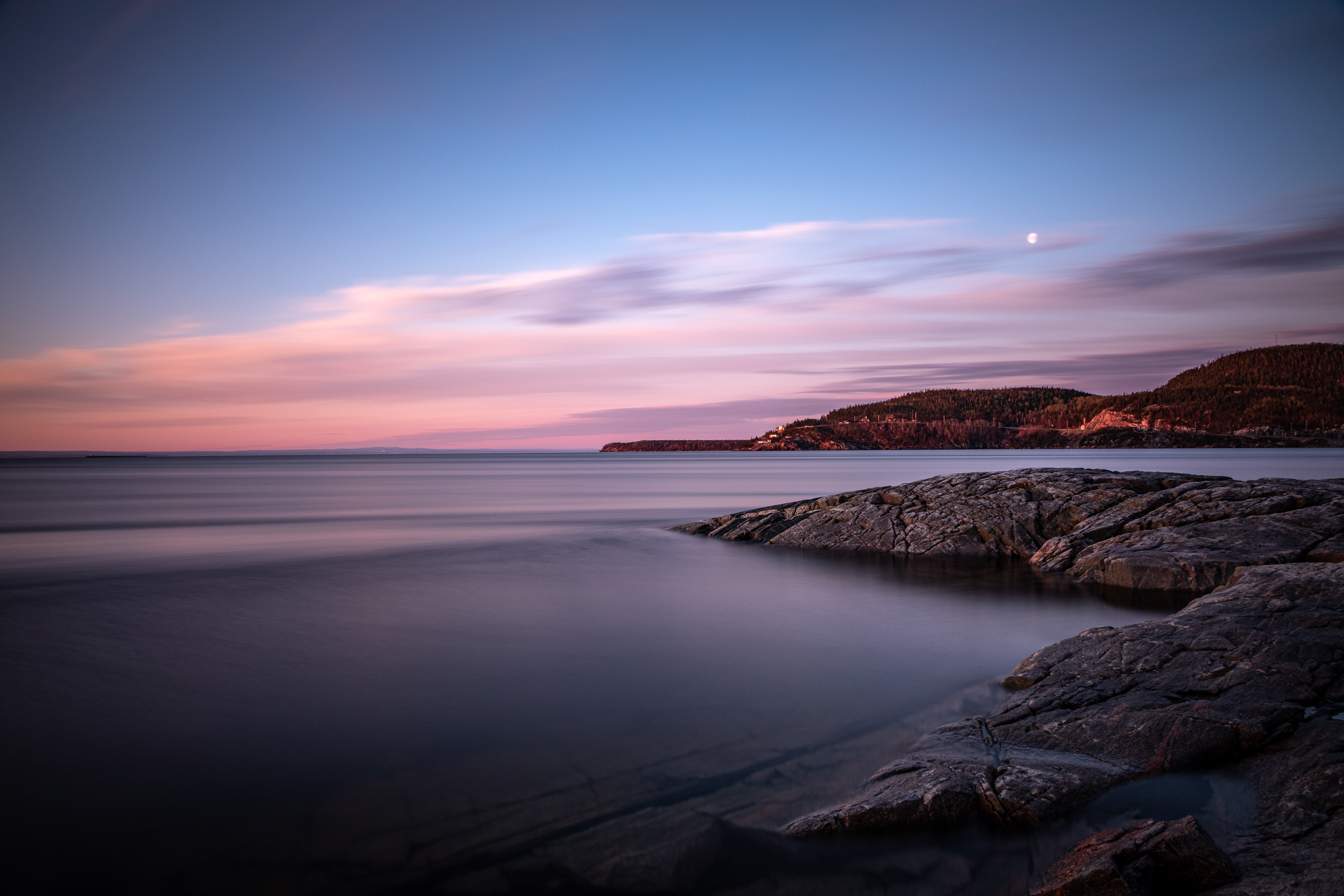 Ocean sunset with rocky shore and distant hills HD Wallpaper